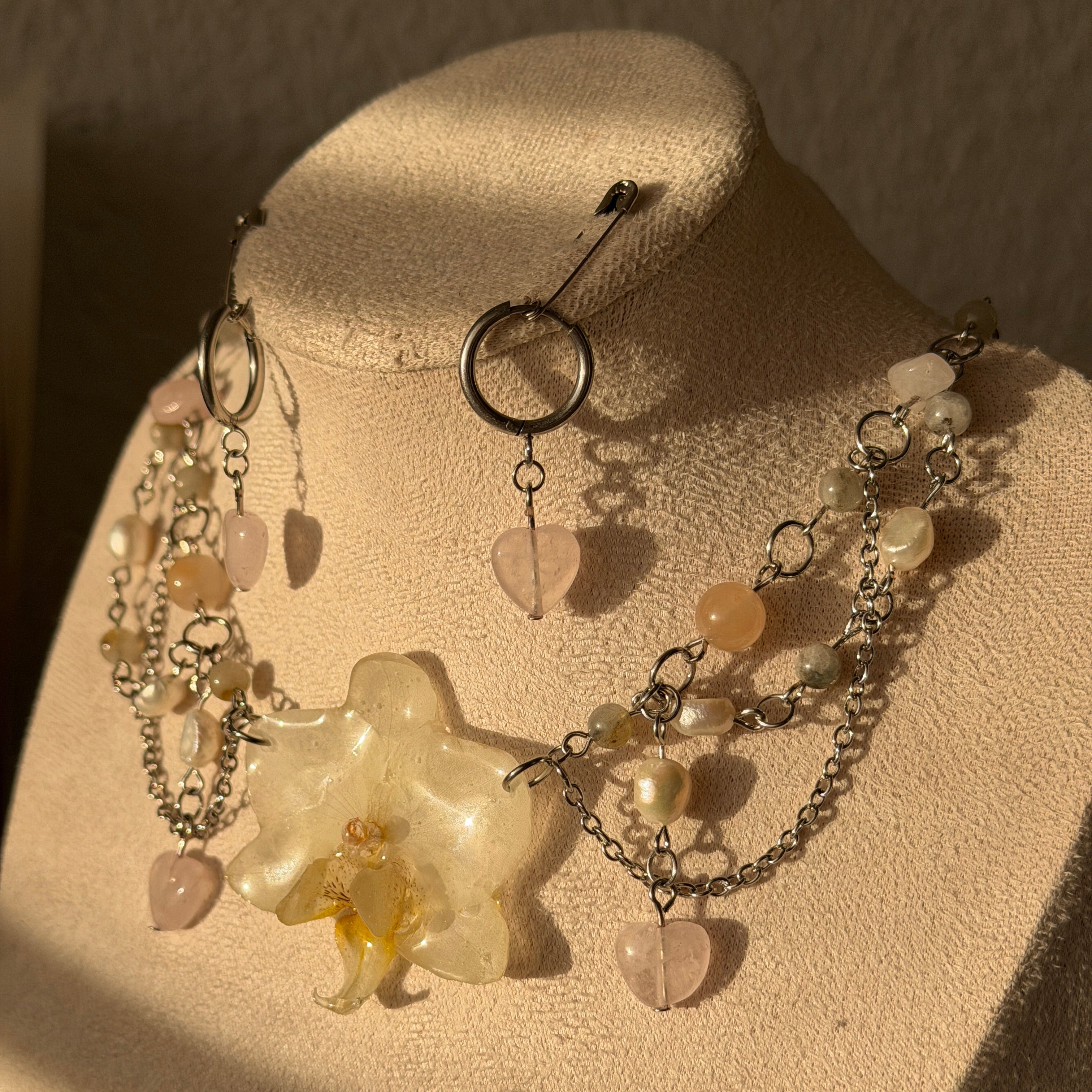 Set Orquídea Niebla en maniquí: collar multicadena plateada con orquídea blanca, cuarzo rosa y perlas, con pendientes corazón