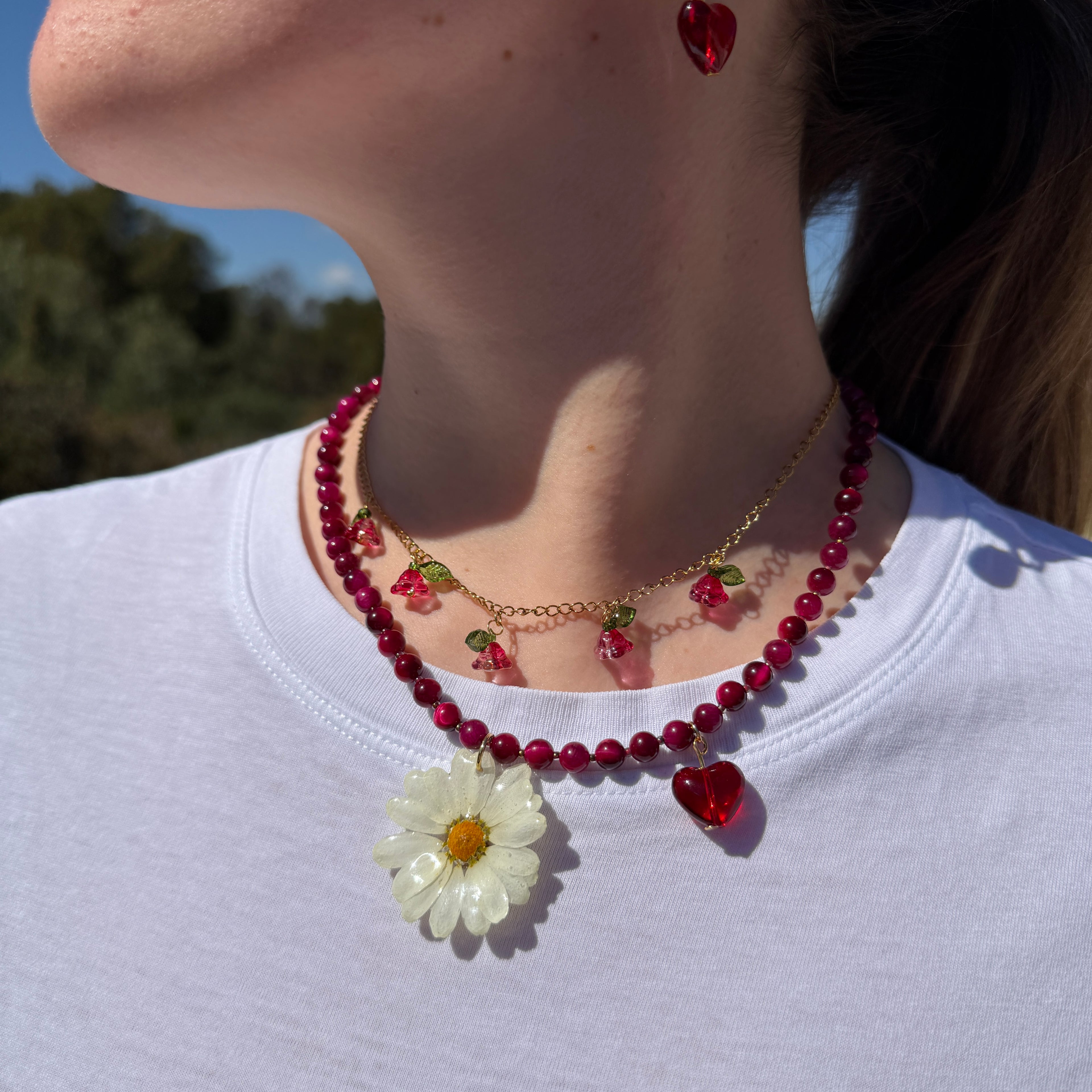 Modelo con el Set Margarita Cereza completo: collar con margarita blanca, collar cerezas dorado y pendientes corazón rojo