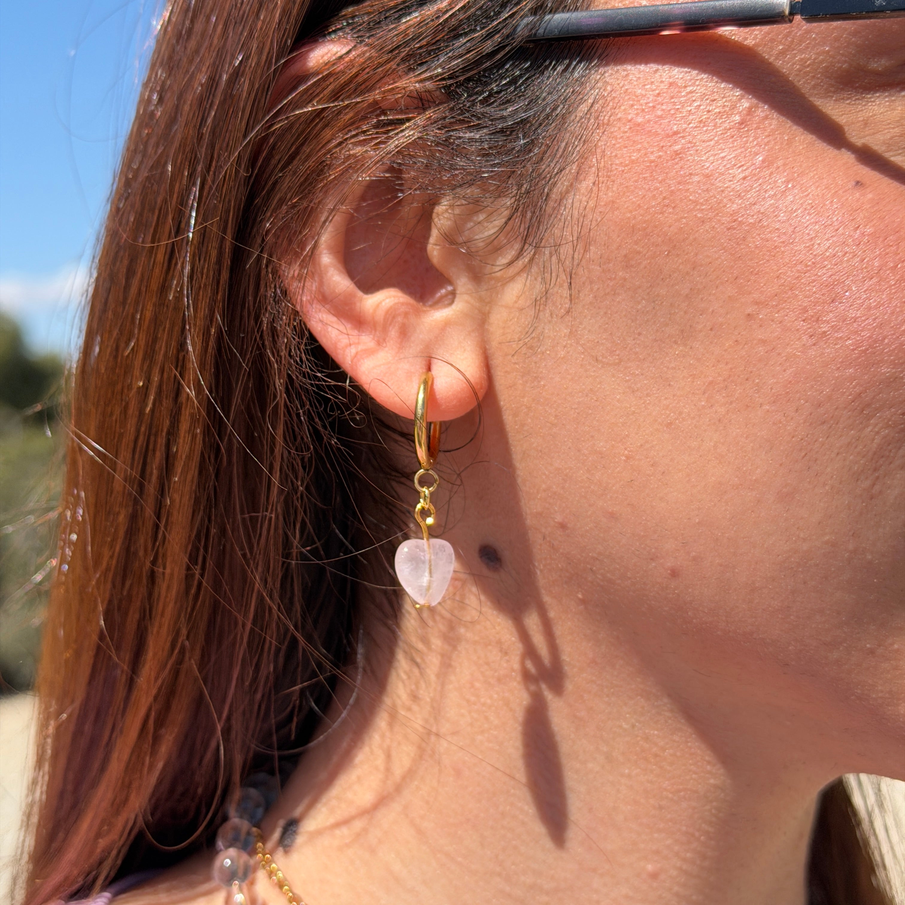 Modelo llevando el Set Margarita Brisa de Aurum Orchid completo con collar de margarita preservada y pendiente huggie dorado con cuarzo rosa al aire libre bajo luz natural