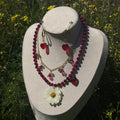 Set Margarita Cereza en maniquí exterior: collar cuentas cereza con margarita blanca, collar dorado con cerezas y pendientes corazón rojo