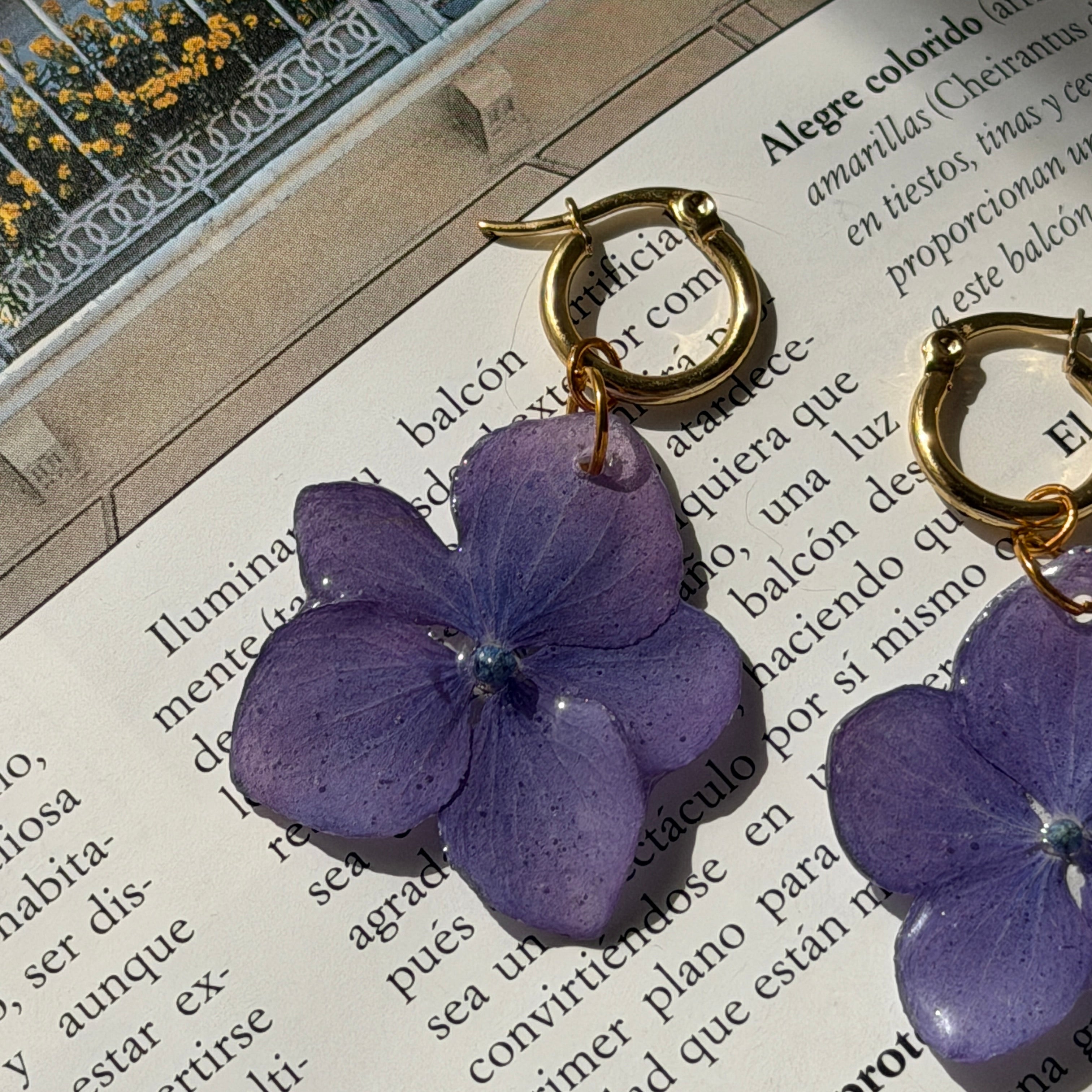 Modelo de espaldas con pendientes de hortensia lavanda en resina, recogido y tatuaje de mariposa