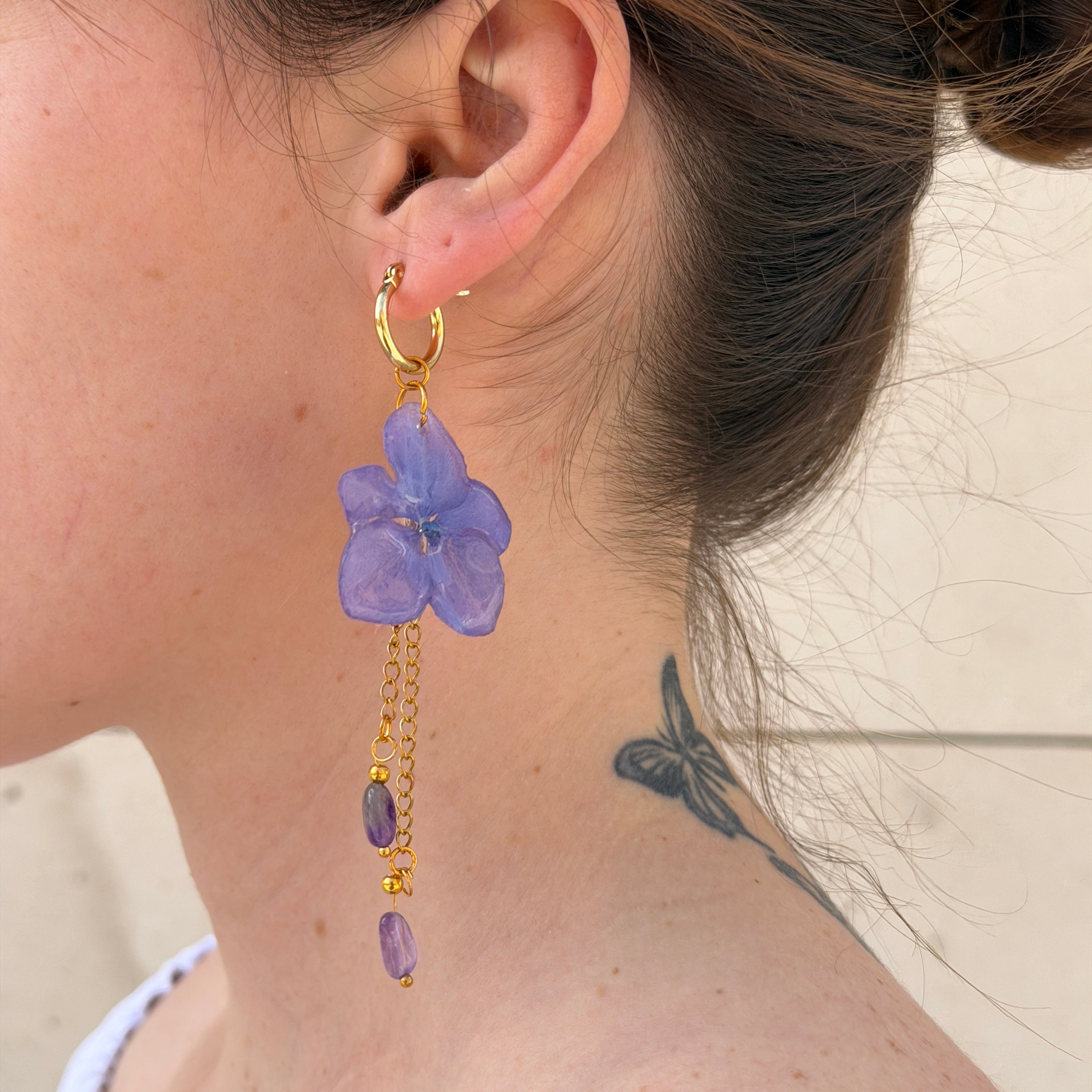 Modelo con Pendientes Hortensia Cascada en oreja, hortensia lavanda con cadenas doradas y amatistas