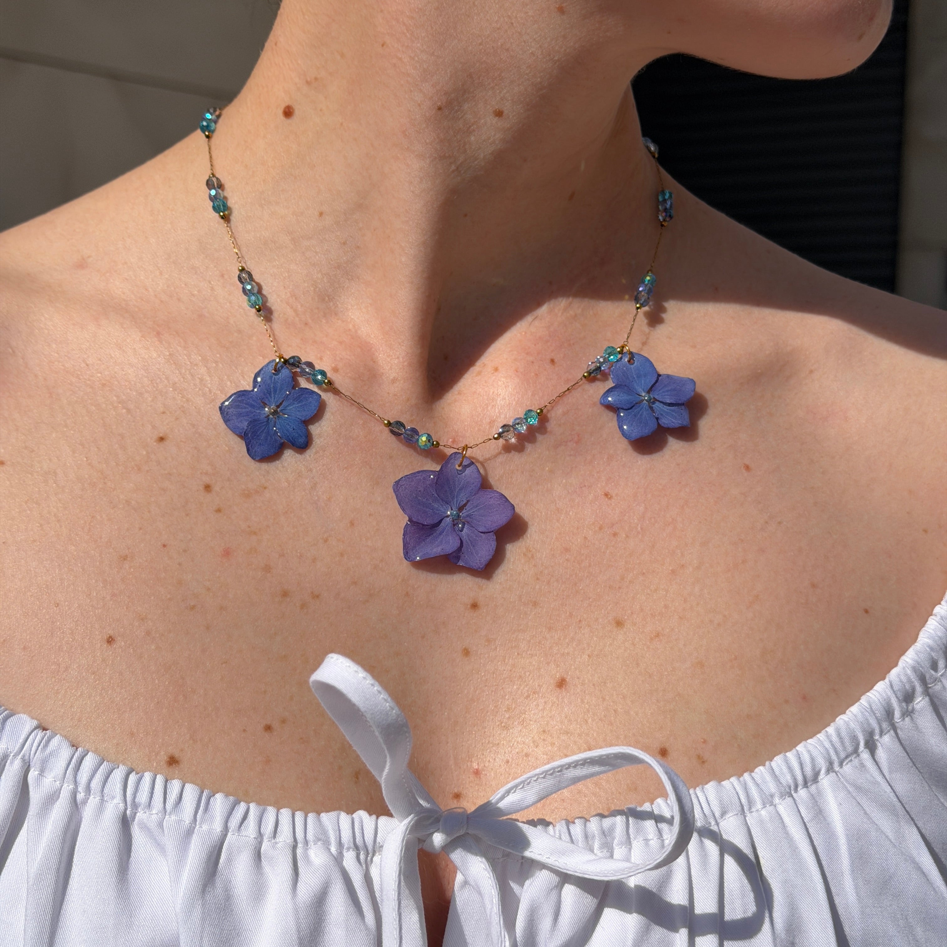 Modelo luciendo Collar Hortensia Celeste con tres flores lavanda y cuentas de cristal azul