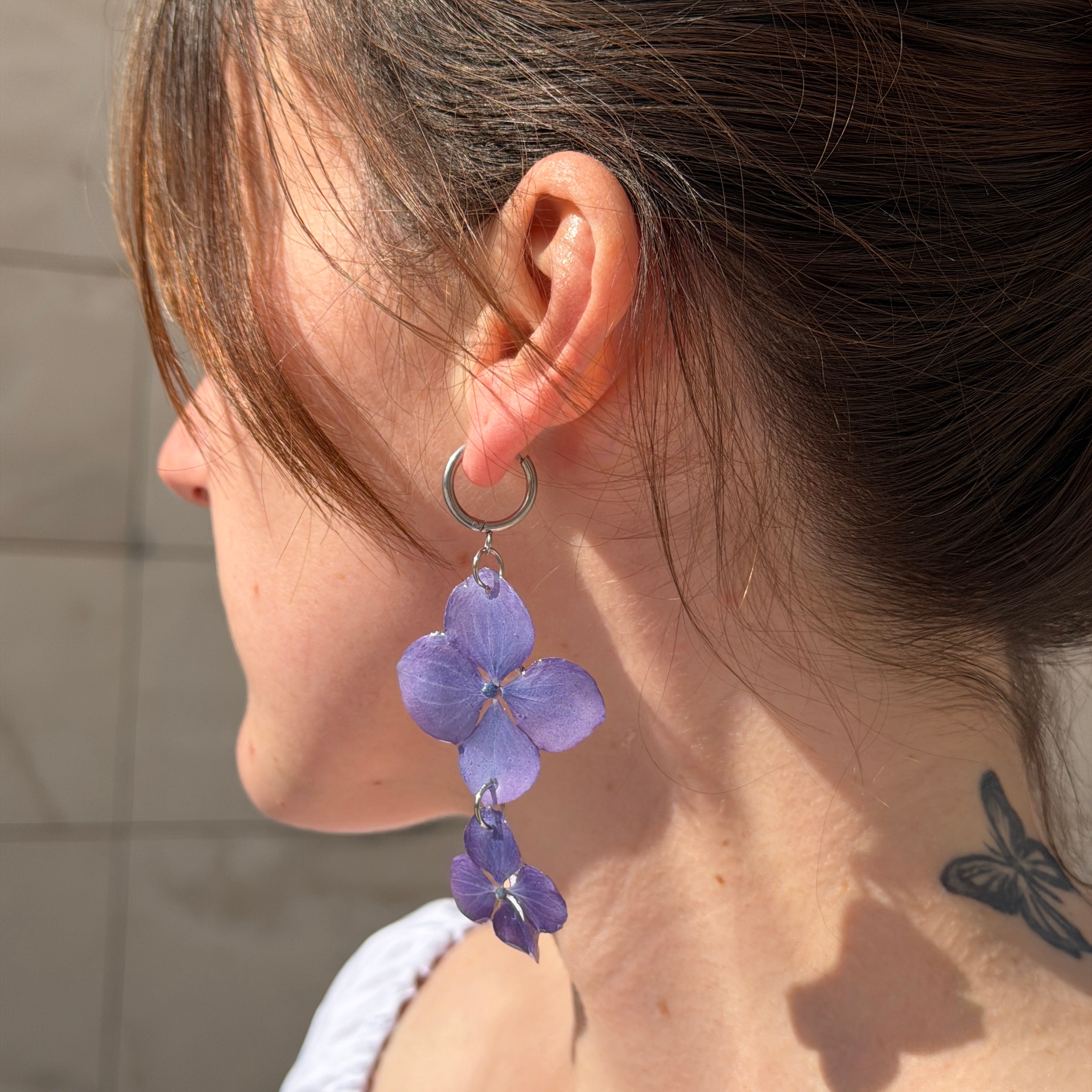 Modelo de espaldas con Pendientes Hortensia Dúo de dos flores lavanda en aro plateado