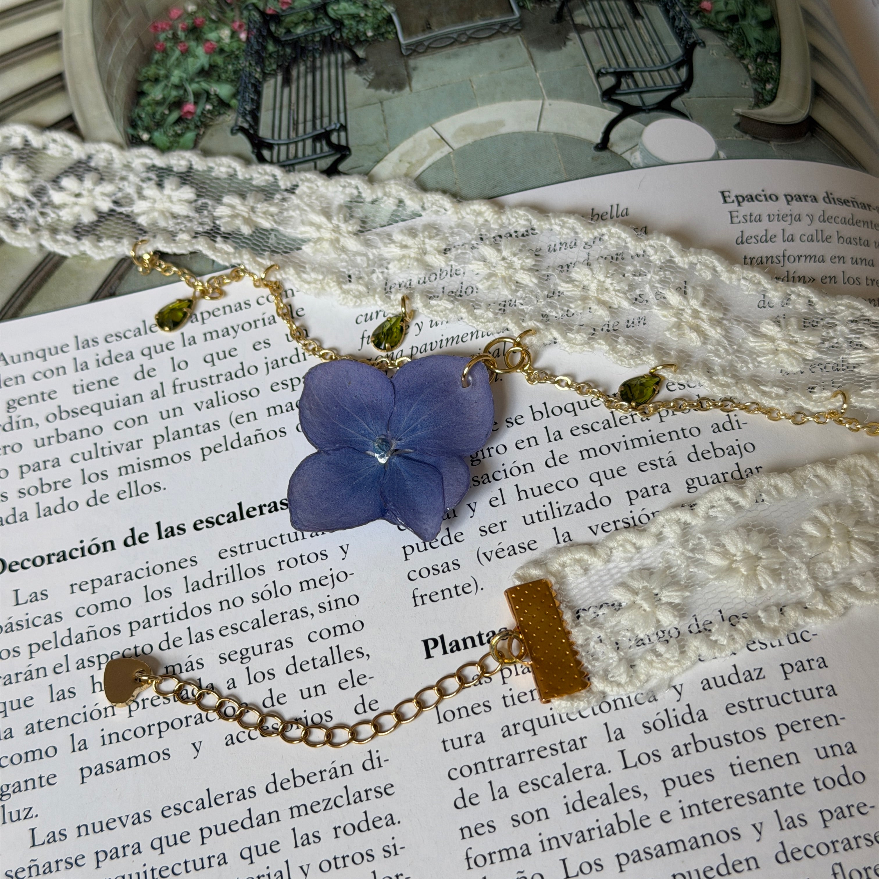 Gargantilla Nocturno sobre libro: encaje crema doble con hortensia lavanda y gotas de cristal verde