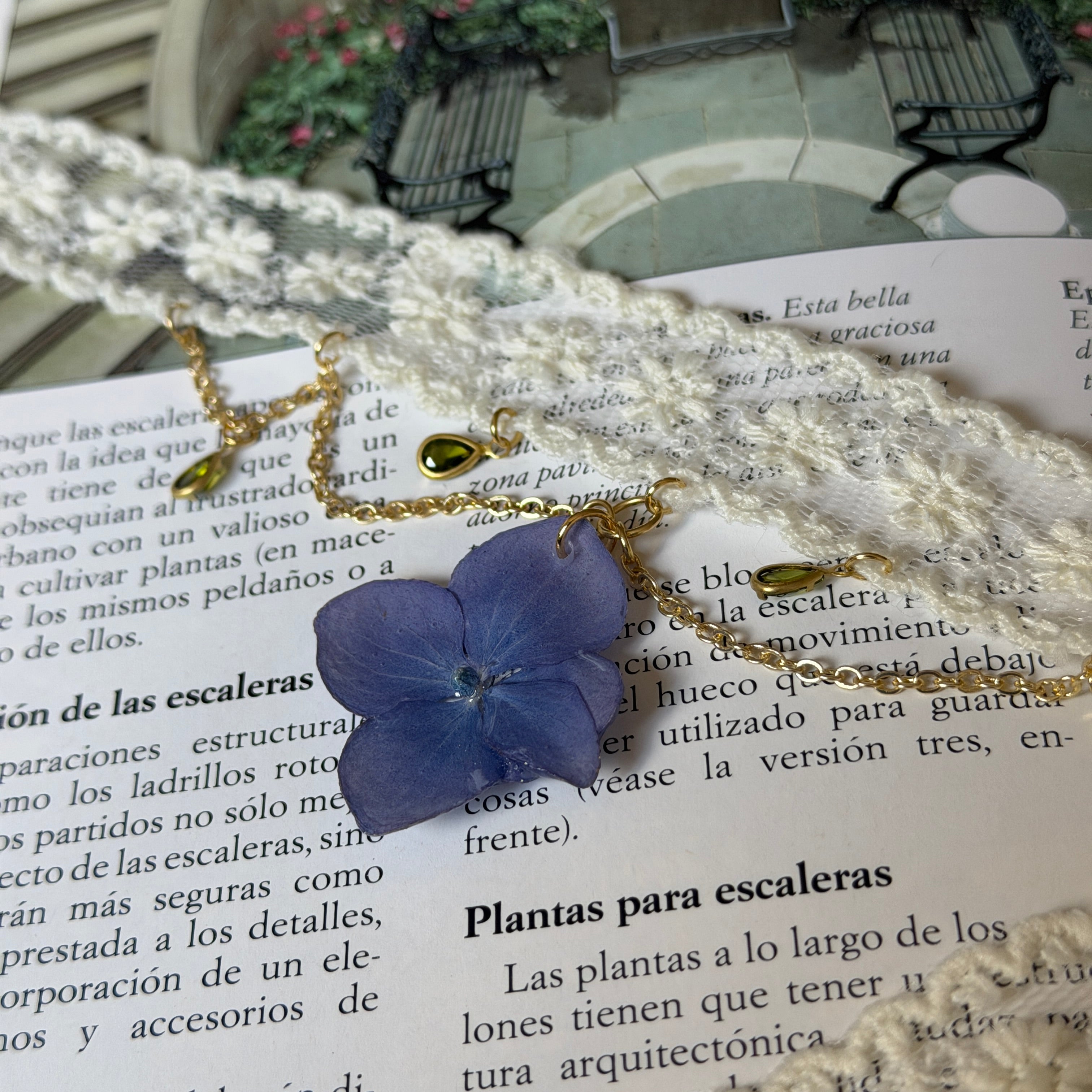 Gargantilla Nocturno sobre libro: encaje crema con hortensia lavanda y cadena dorada con gotas verdes