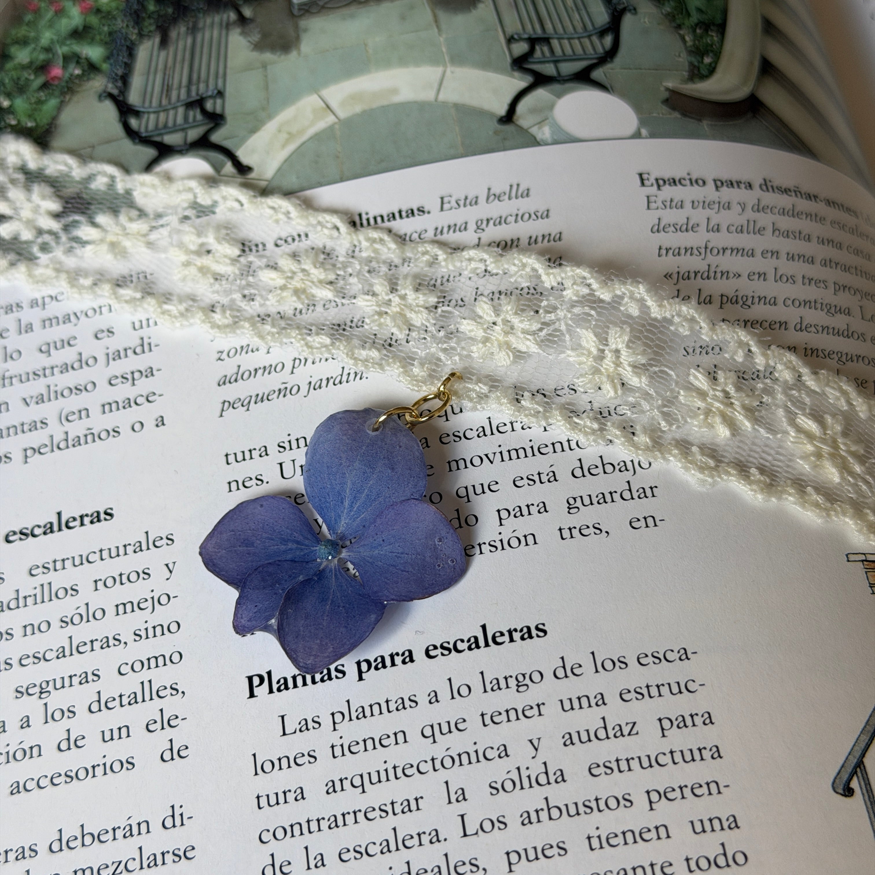 Gargantilla Hortensia Soneto: encaje crema con colgante de hortensia lavanda azul sobre libro