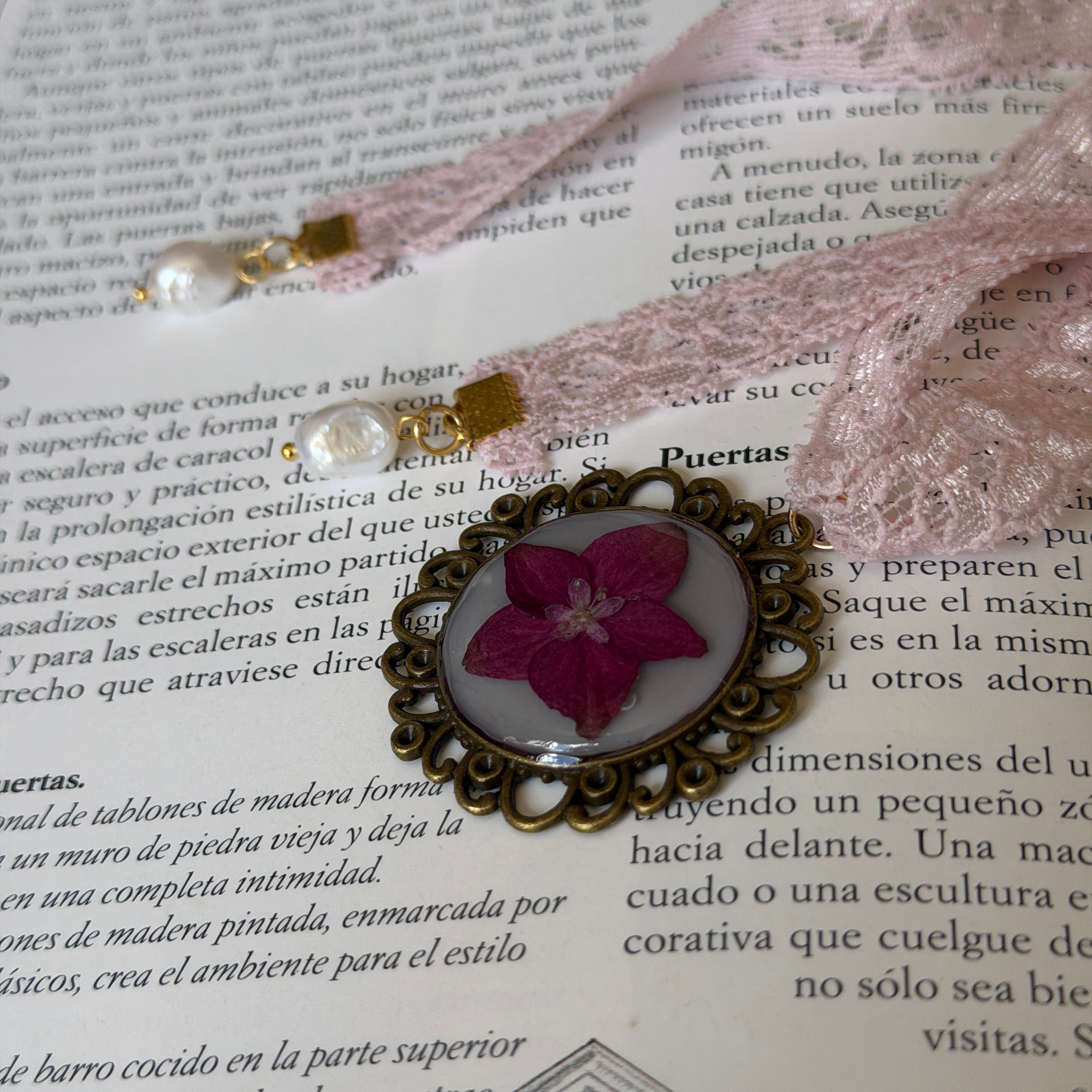 Gargantilla Serenata sobre libro: encaje rosa con medallón bronce, hortensia fucsia y perlas barrocas