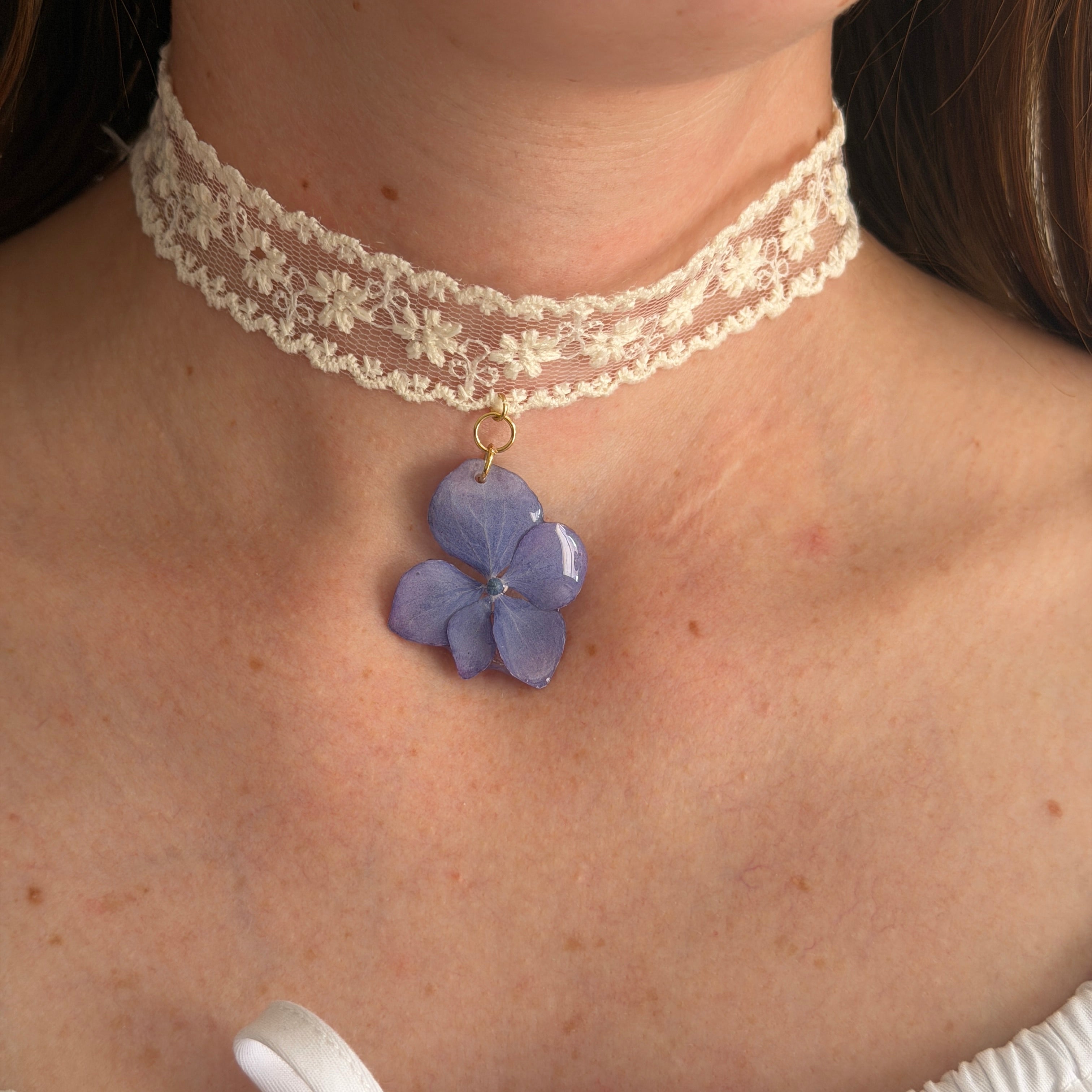 Modelo con Gargantilla Hortensia Soneto: encaje crema con colgante de hortensia azul lavanda en resina