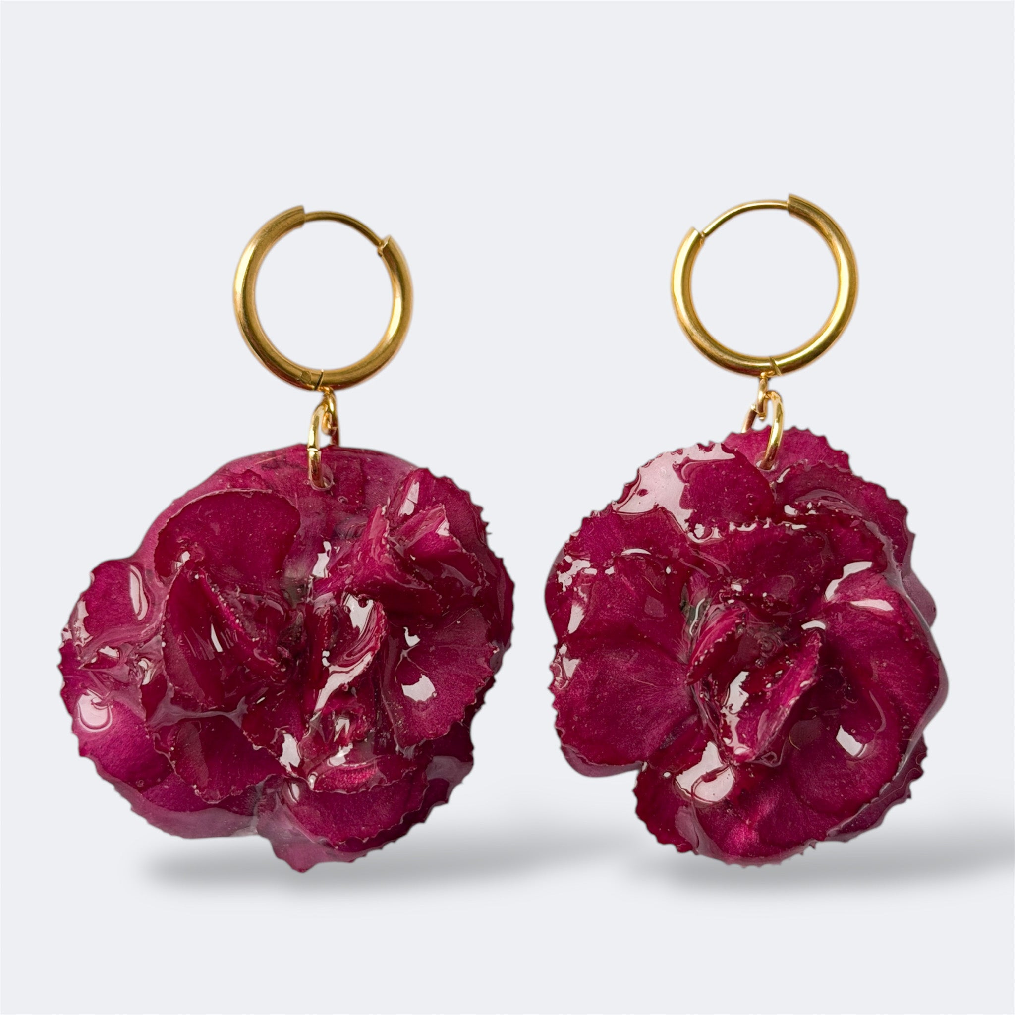 Detalle de pendientes Clavel Fulgor con aro dorado y flor natural preservada