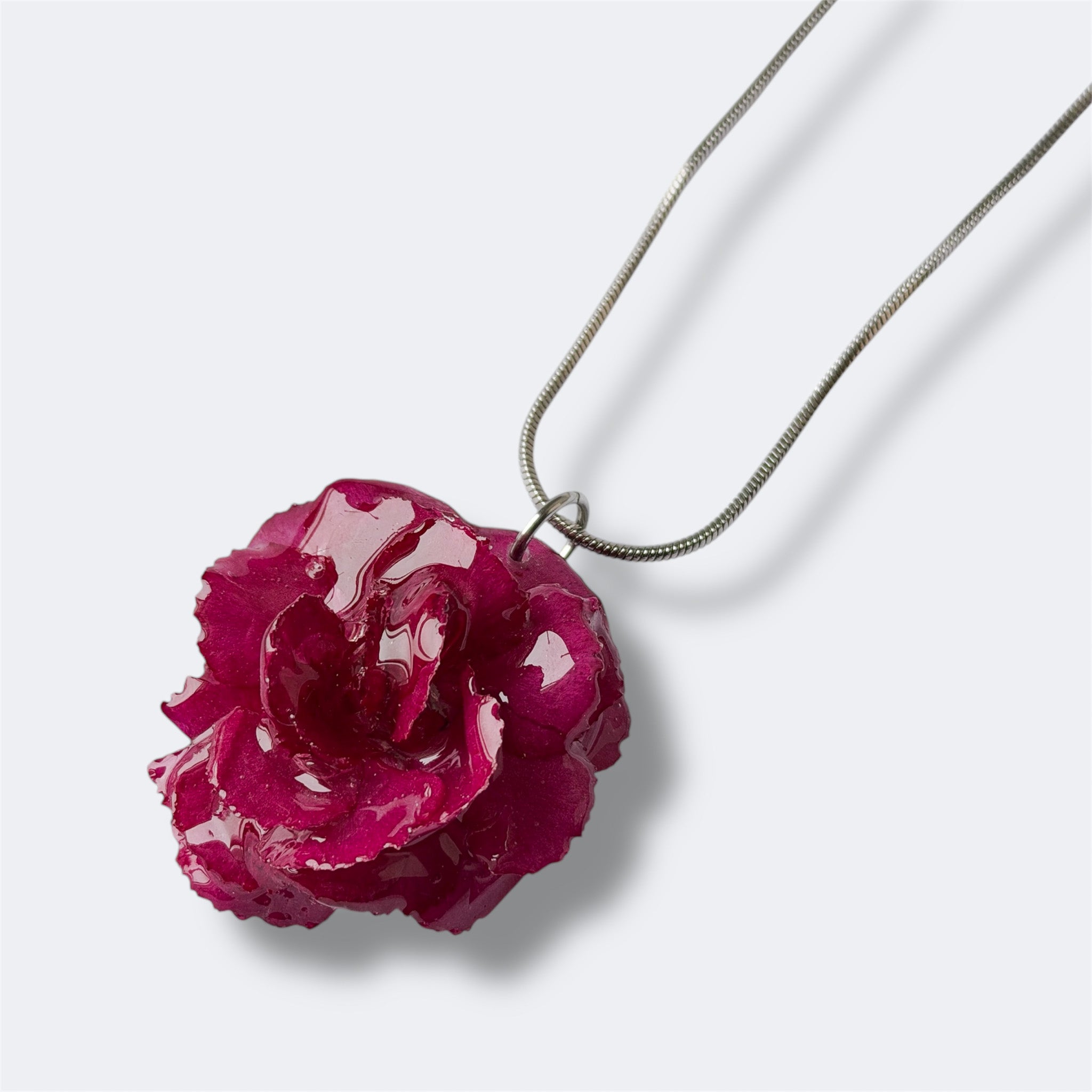 Detalle collar Clavel Fulgor con clavel natural fucsia encapsulado en resina