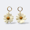 Par de pendientes de margarita blanca sencillos en aros dorados, fondo gris