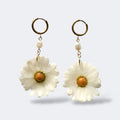 Par de pendientes de margarita blanca con perla natural barroca en aros dorados, fondo gris