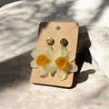 Par de Pendientes Narciso Alborada con flor de narciso blanco-amarilla preservada en resina, sobre tarjeta kraft y piedra