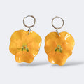 Par de Pendientes Pensamiento Candela con flor amarillo intenso en aros plateados, fondo gris