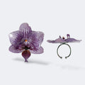 Anillo de orquídea natural preservada en resina lila malva con venas detalladas, vista frontal y lateral, fondo blanco