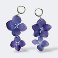 Par de Pendientes Hortensia Dúo: dos flores lavanda apiladas colgando de aros plateados, fondo gris