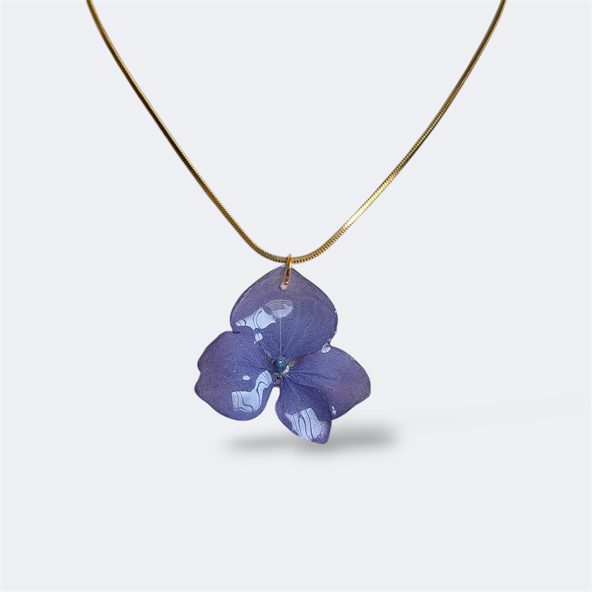 Collar colgante de hortensia lavanda natural preservada en resina con cadena serpiente dorada, fondo gris