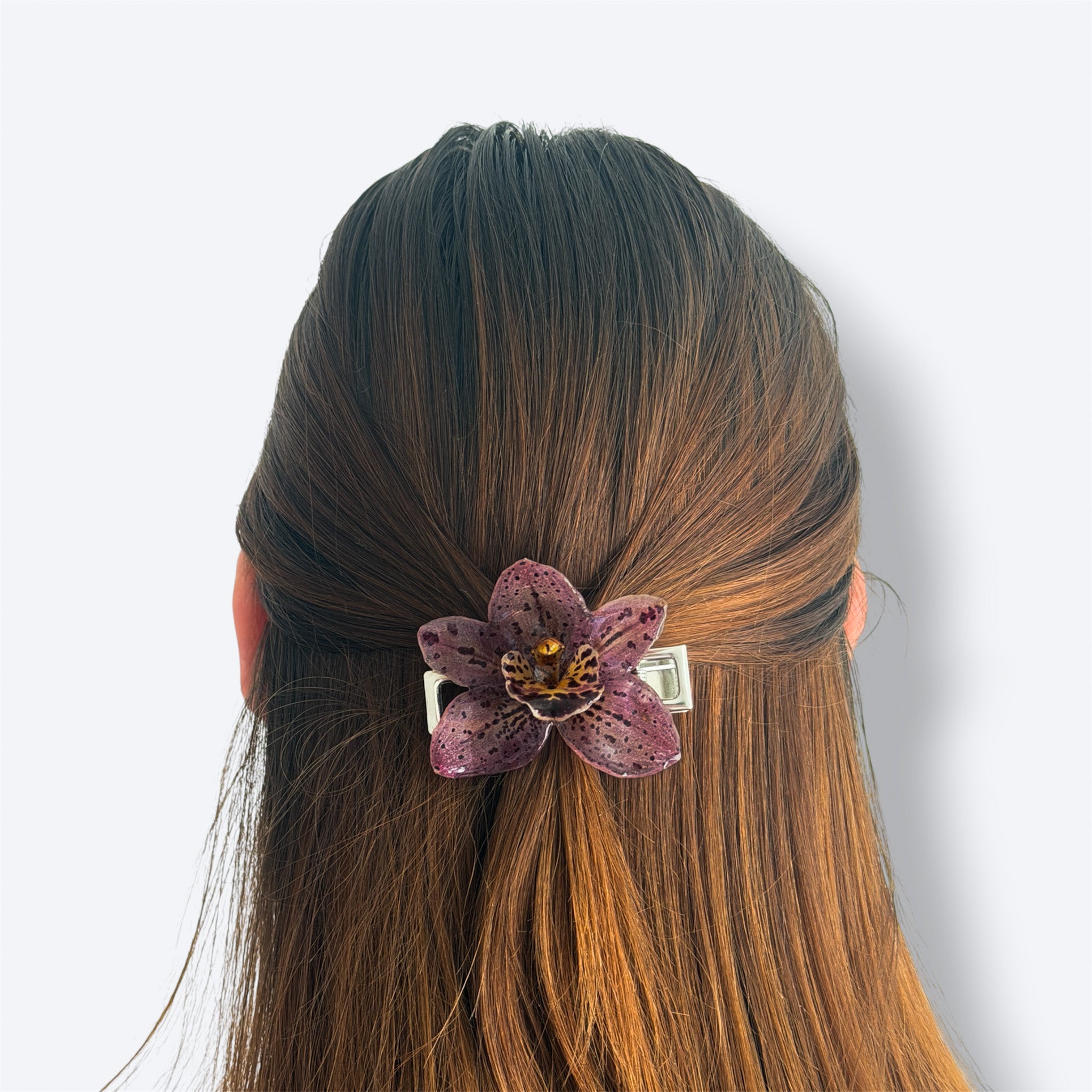 Modelo con Pinza Orquídea Velaria en pelo liso castaño, orquídea marrón con manchas, media coleta