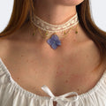 Modelo con Gargantilla Nocturno: encaje crema doble con hortensia lavanda, cadena dorada y gotas verdes