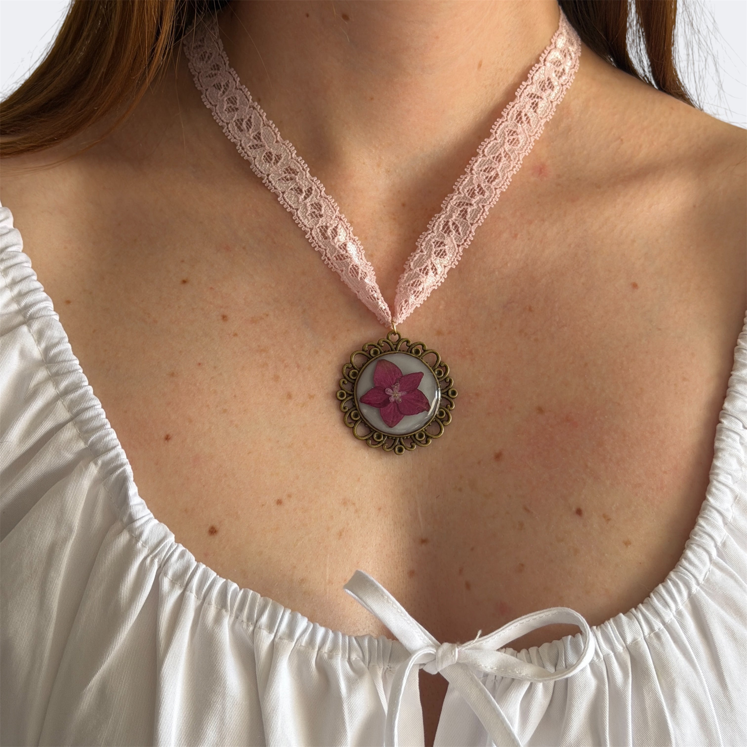 Modelo con Gargantilla Serenata: encaje rosa palo con medallón bronce de hortensia fucsia en resina