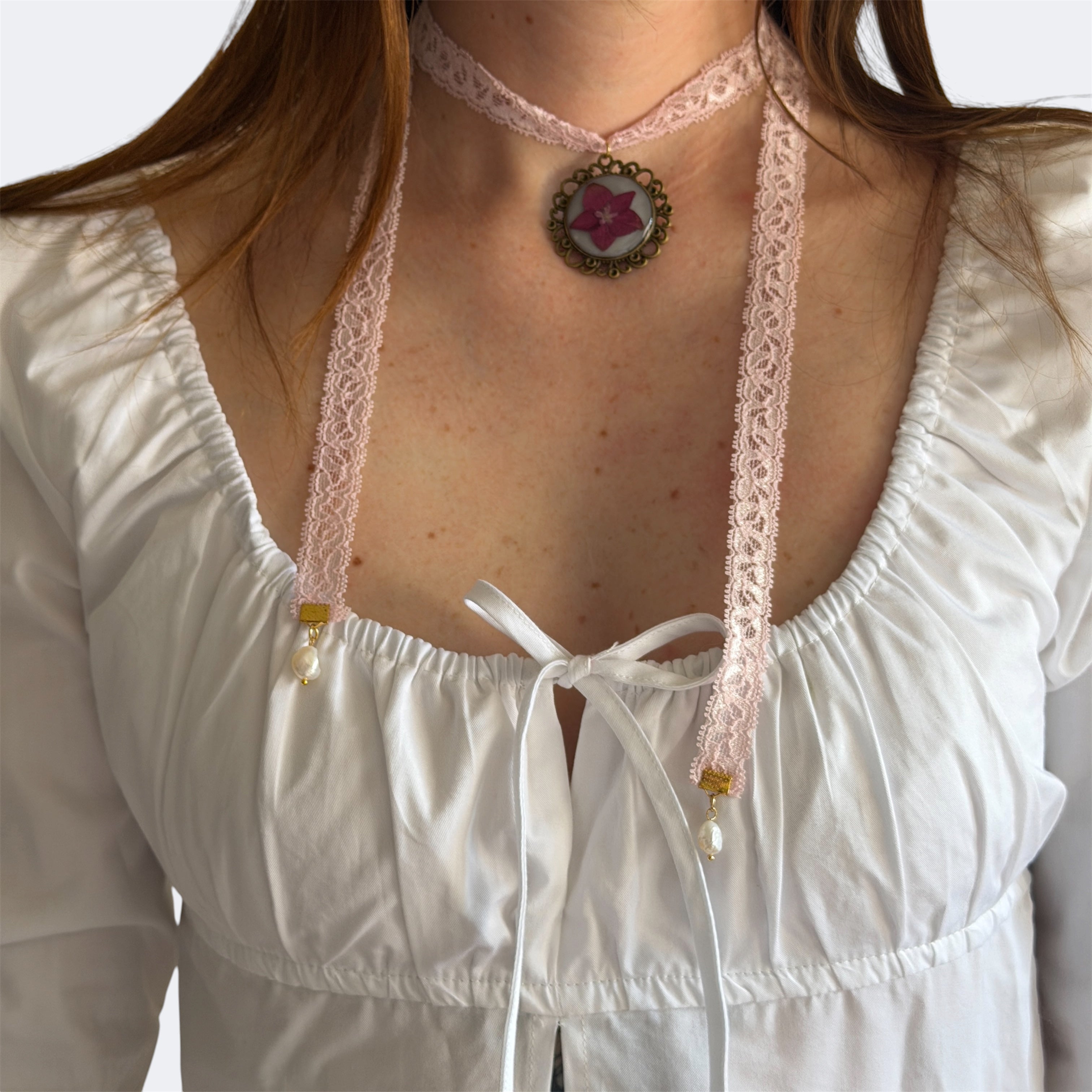 Modelo con Gargantilla Serenata de frente: encaje rosa, medallón bronce con hortensia fucsia y perlas