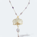 Collar con orquídea blanca encapsulada en resina, sobre cadena de acero inoxidable con piedras naturales violetas y perlas
