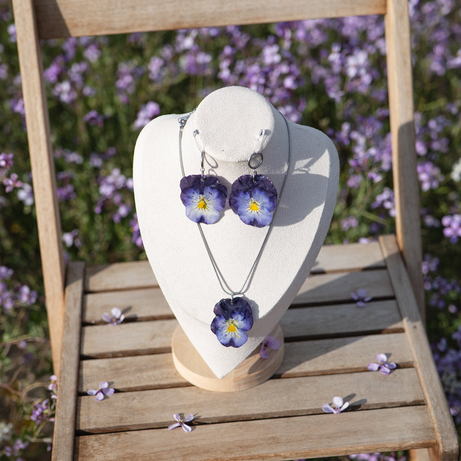 Maniquí con collar y pendientes Pensamiento Violeta sobre silla de jardín, fondo de lavanda