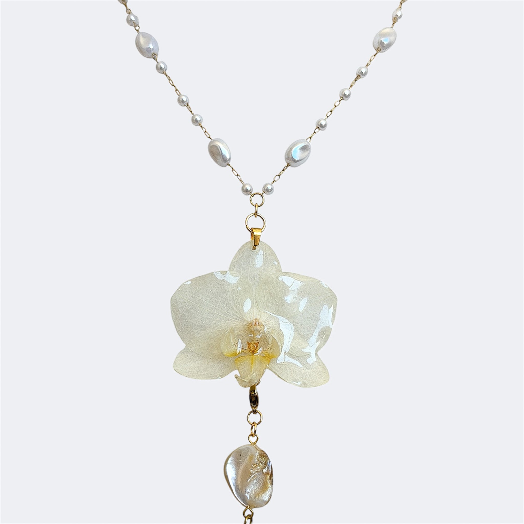 Detalle de perla barroca de agua dulce como remate de collar largo con orquidea marfil