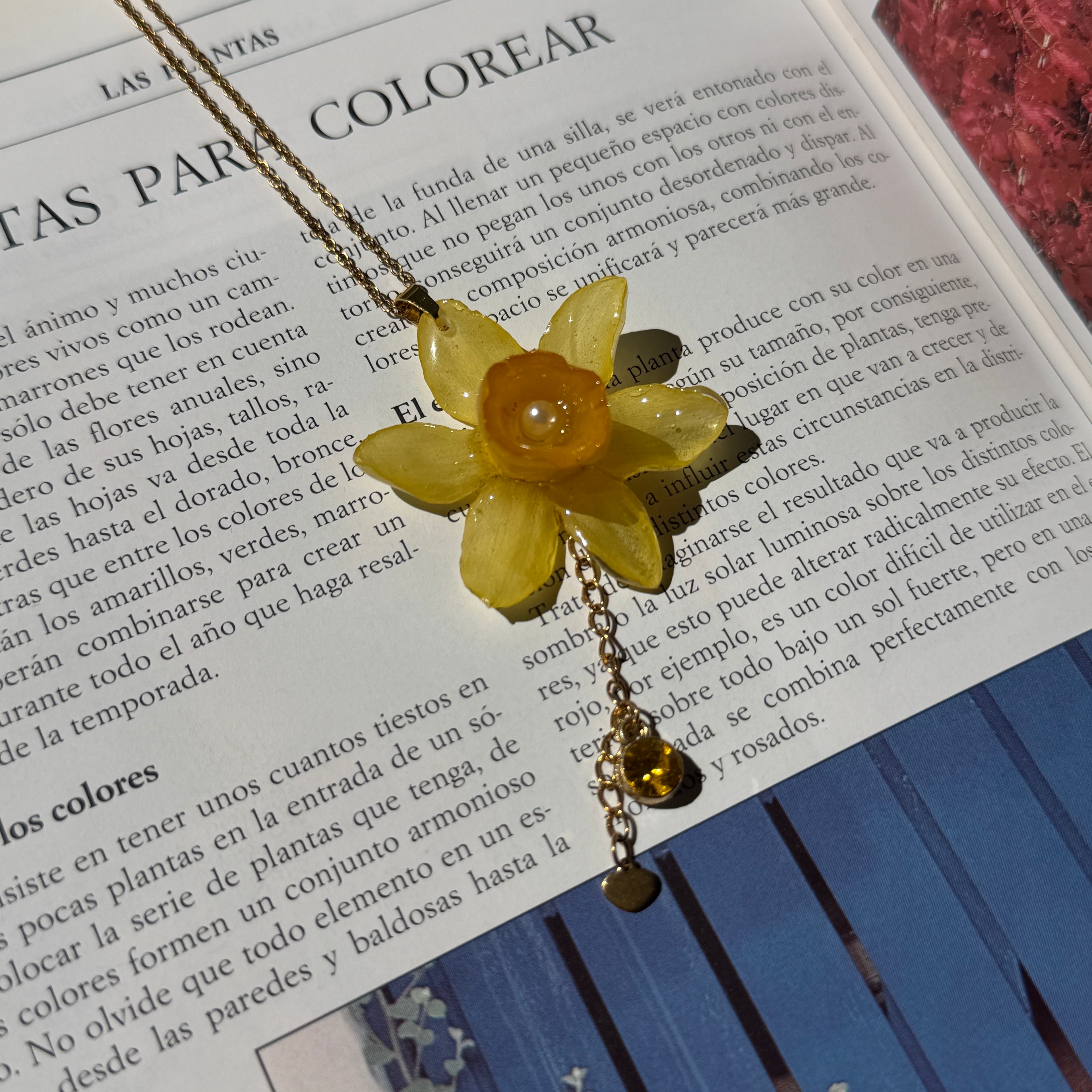Detalle de narciso amarillo real preservado en resina, con trompeta naranja y perla en el centro