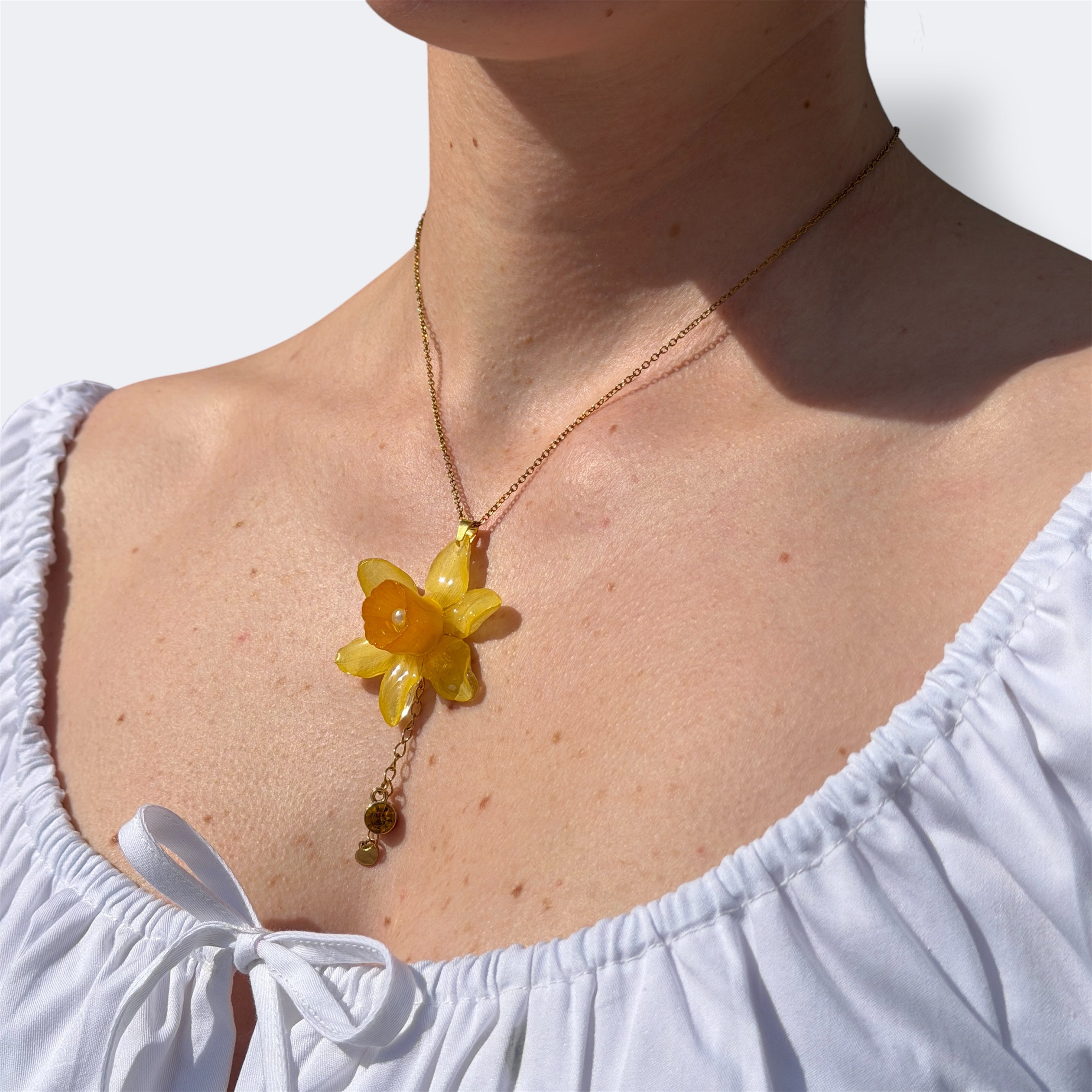 Collar de narciso amarillo encapsulado en resina sobre revista botanica abierta