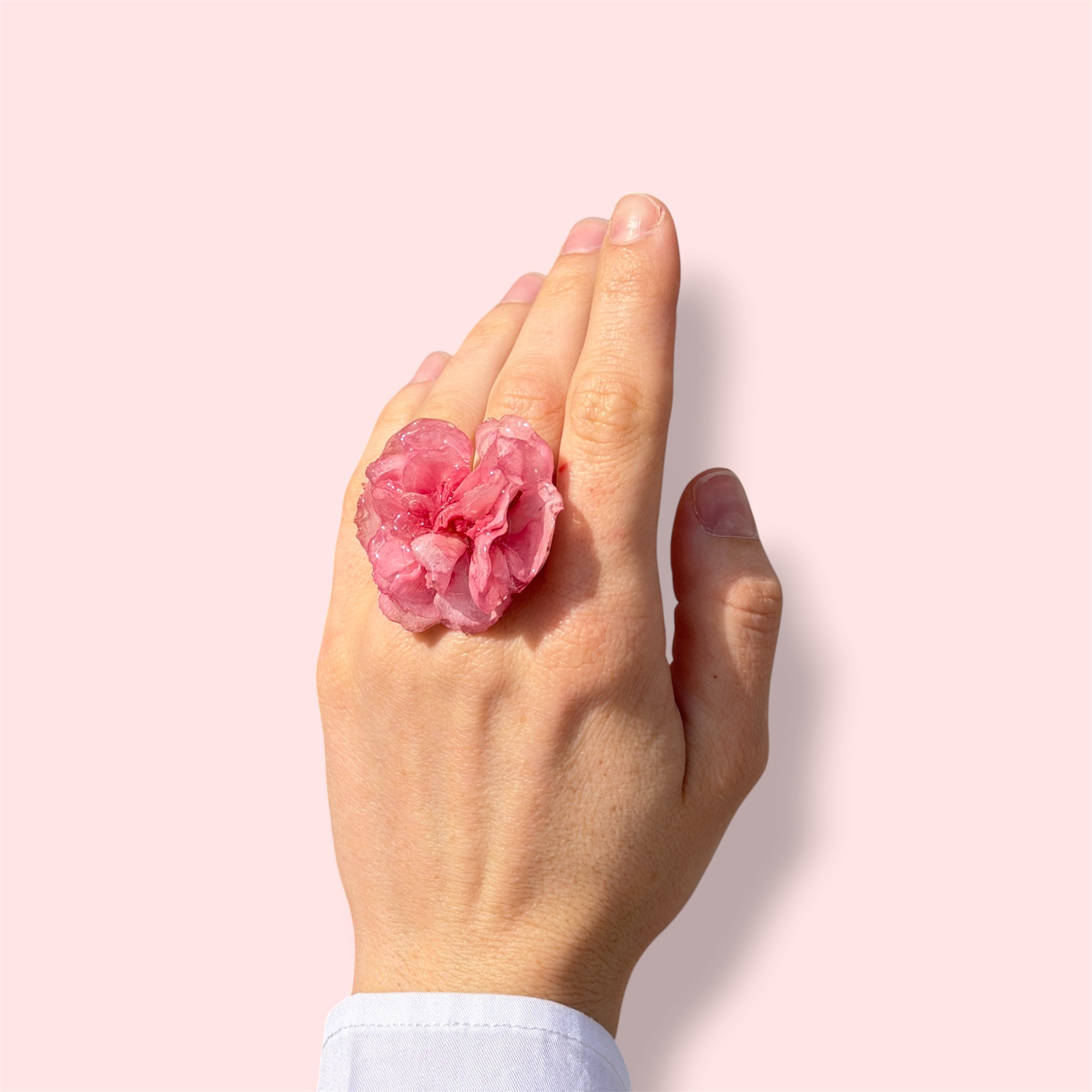 Mujer llevando anillo de clavel rosa encapsulado en resina sobre el dedo
