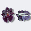 Pinza de orquidea morada encapsulada en resina sobre revista botanica abierta