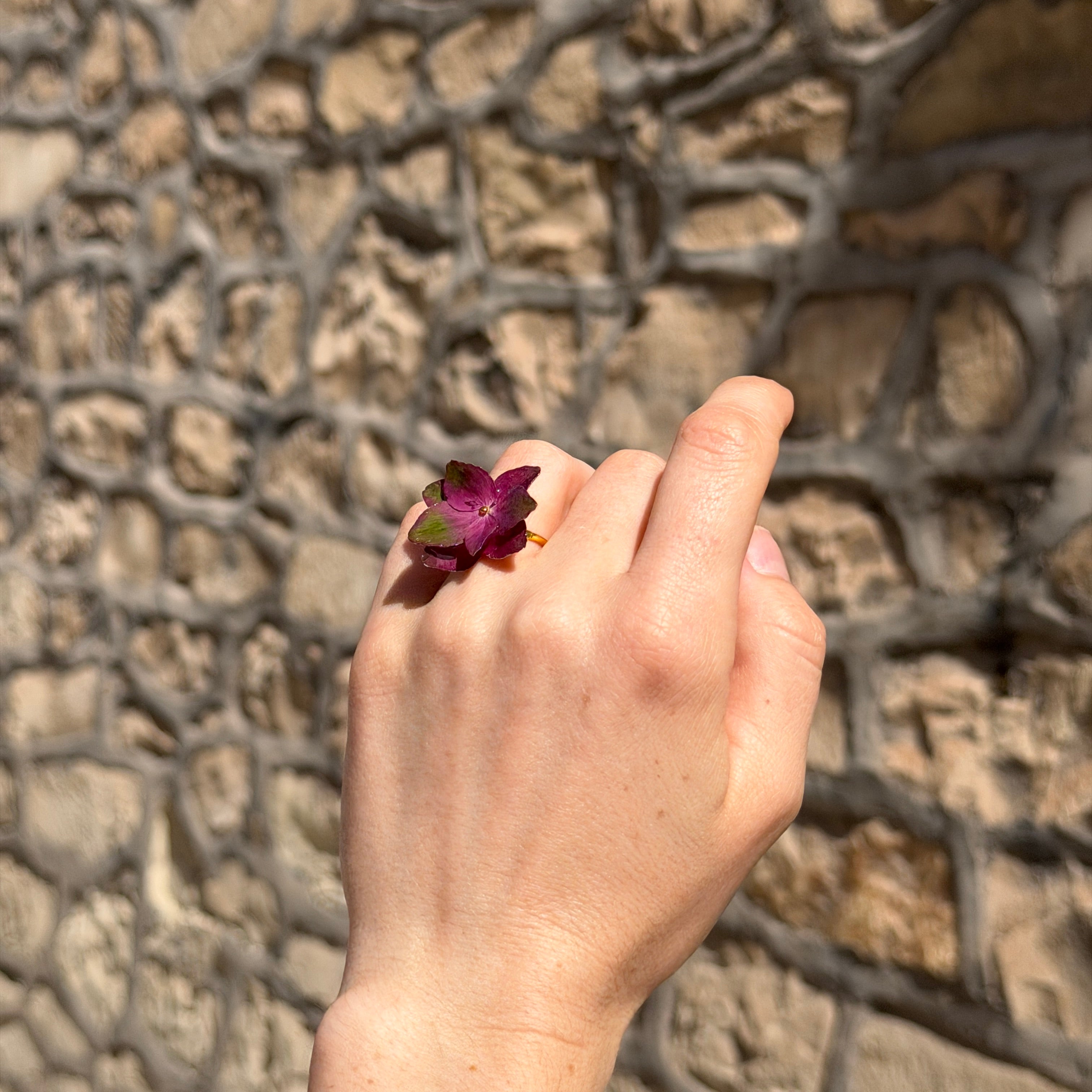 Mujer llevando anillo de hortensias magenta y verdes encapsuladas en resina en el dedo