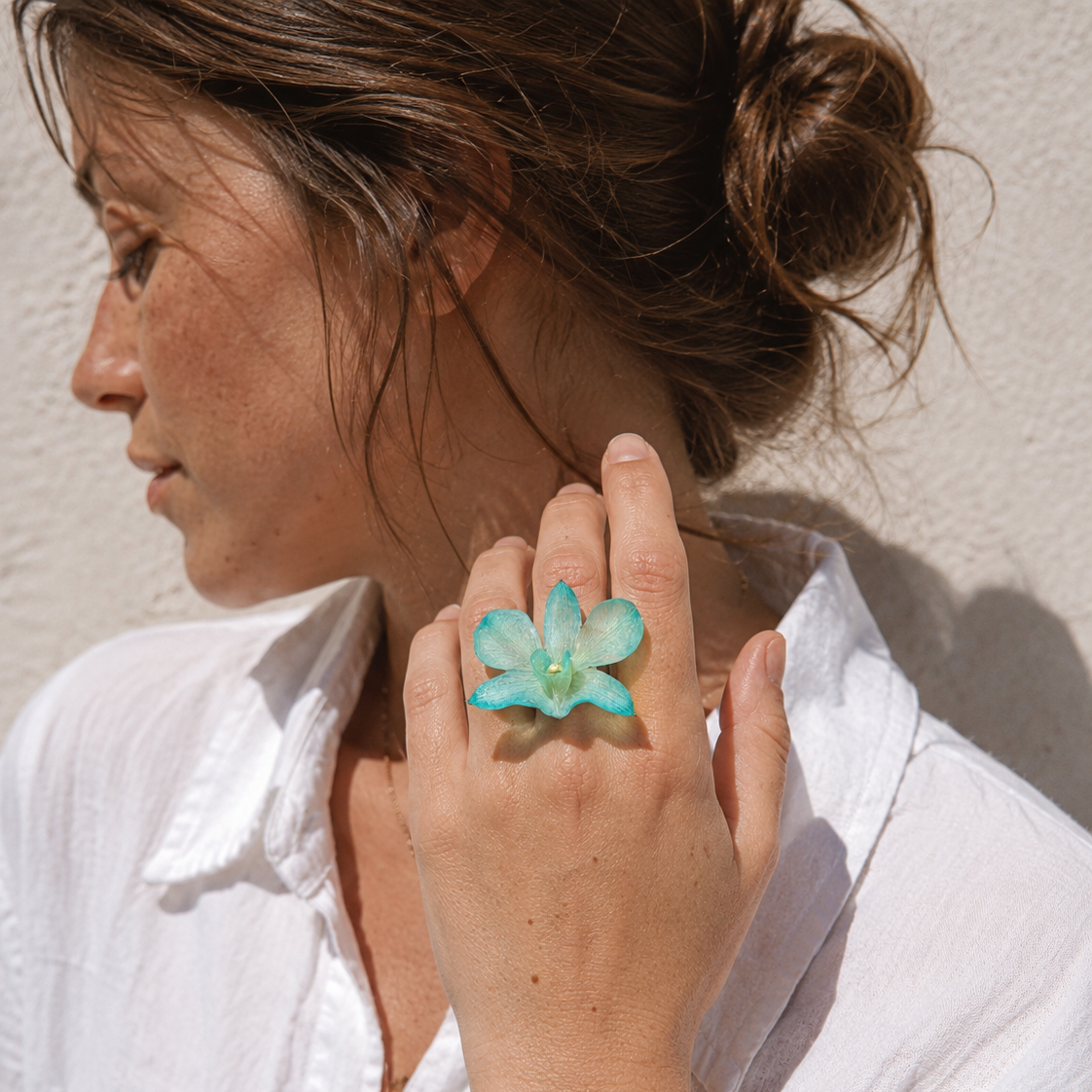 Mujer llevando anillo de orquídea turquesa encapsulada en resina en el dedo