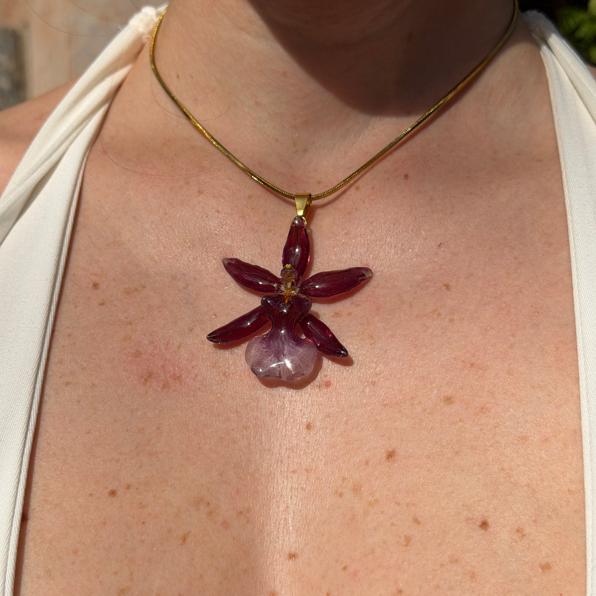 Collar con orquídea Cambria burdeos encapsulada en resina, sobre cadena fina de acero inoxidable