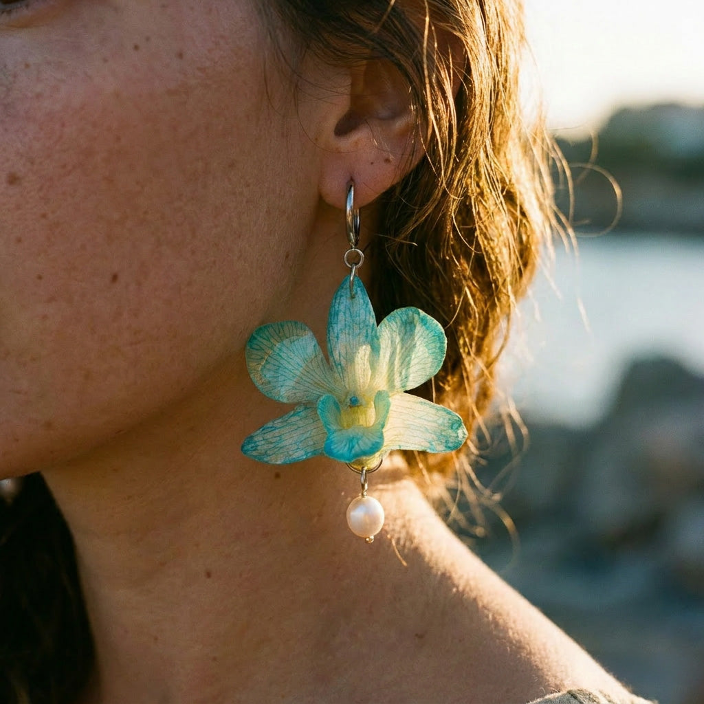 Mujer llevando pendiente de orquídea turquesa encapsulada en resina con perla colgante sobre la oreja