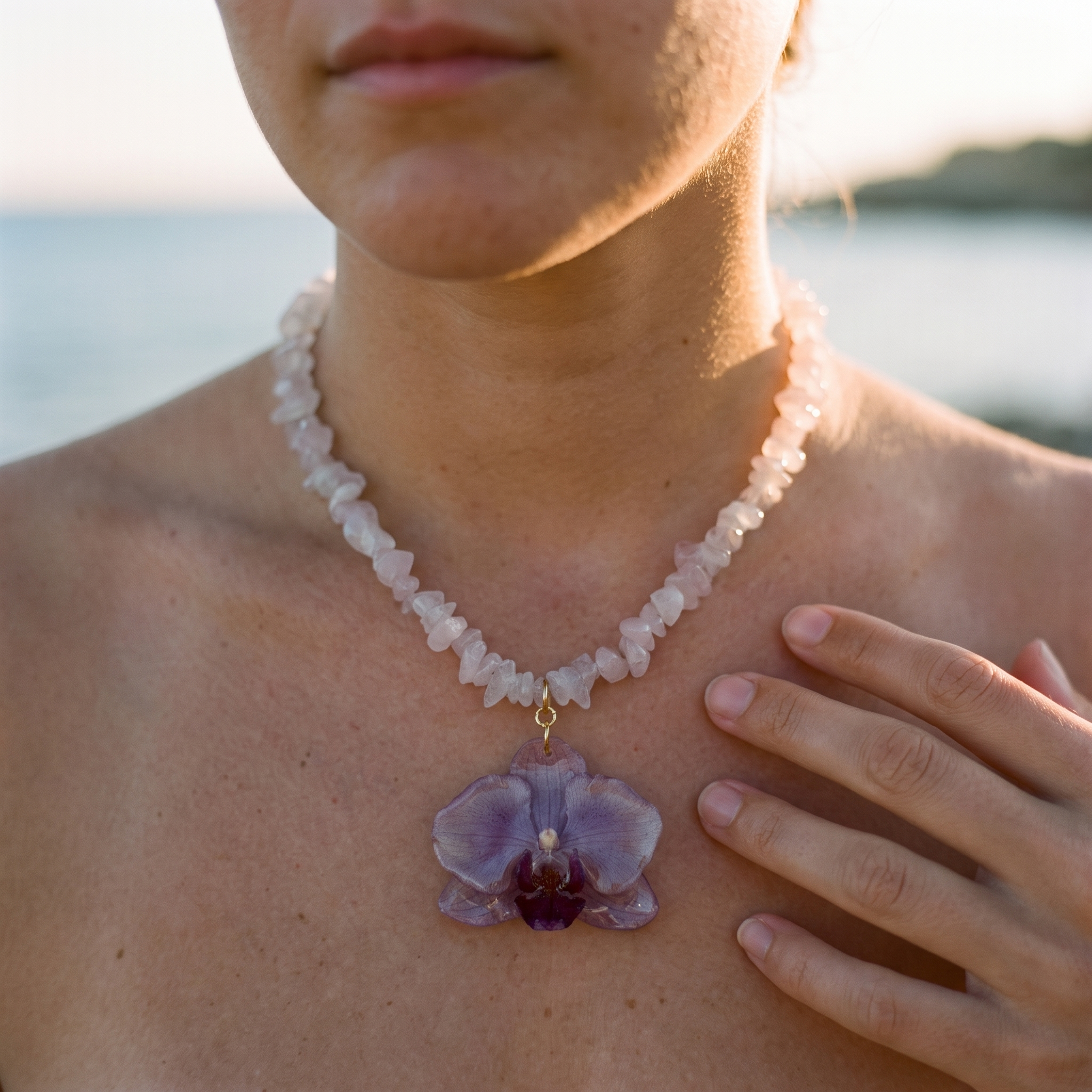 Collar de cuarzo rosa con colgante de orquídea violeta real preservada en resina sobre el pecho