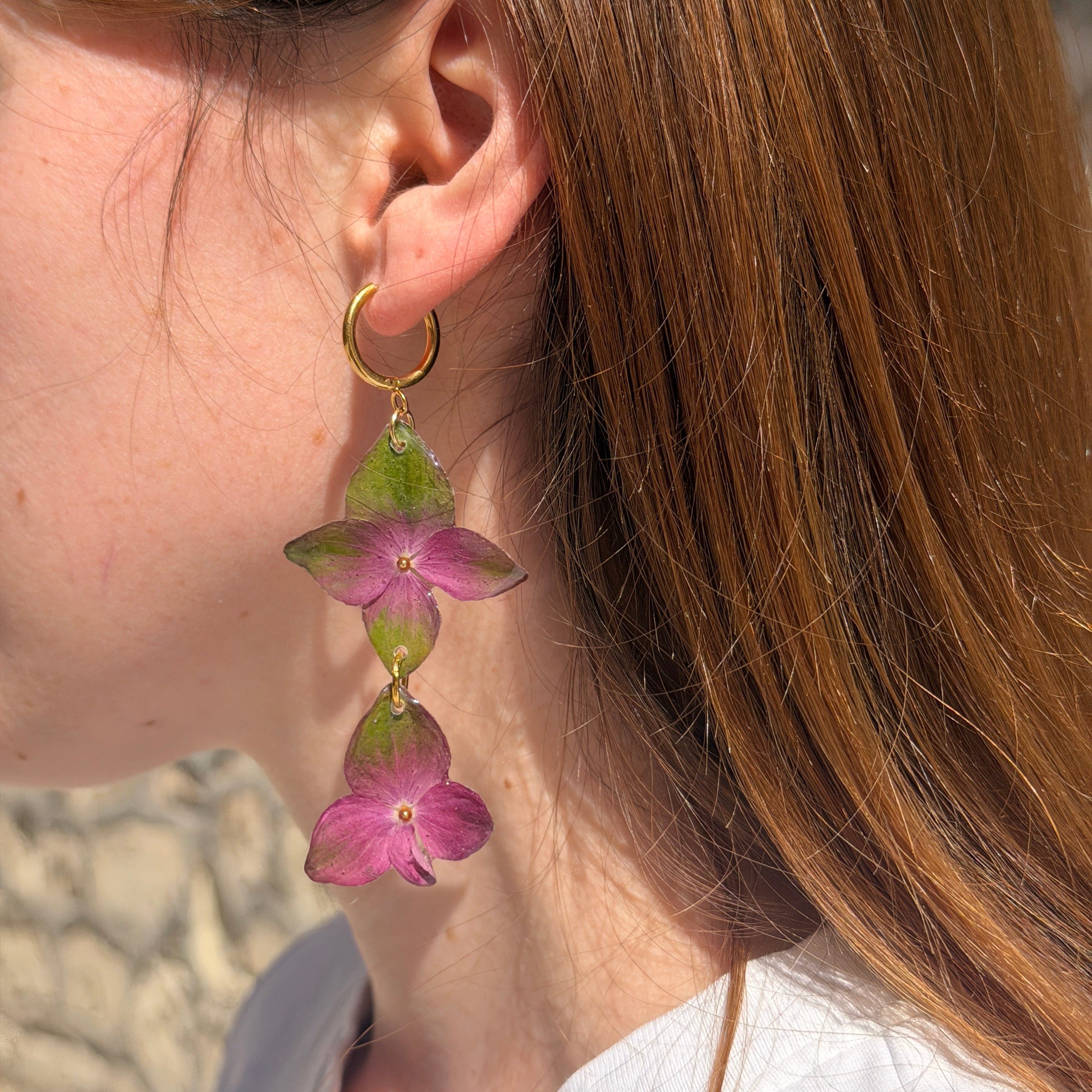 Pendiente de hortensia verde y fucsia en cascada sobre la oreja de una modelo