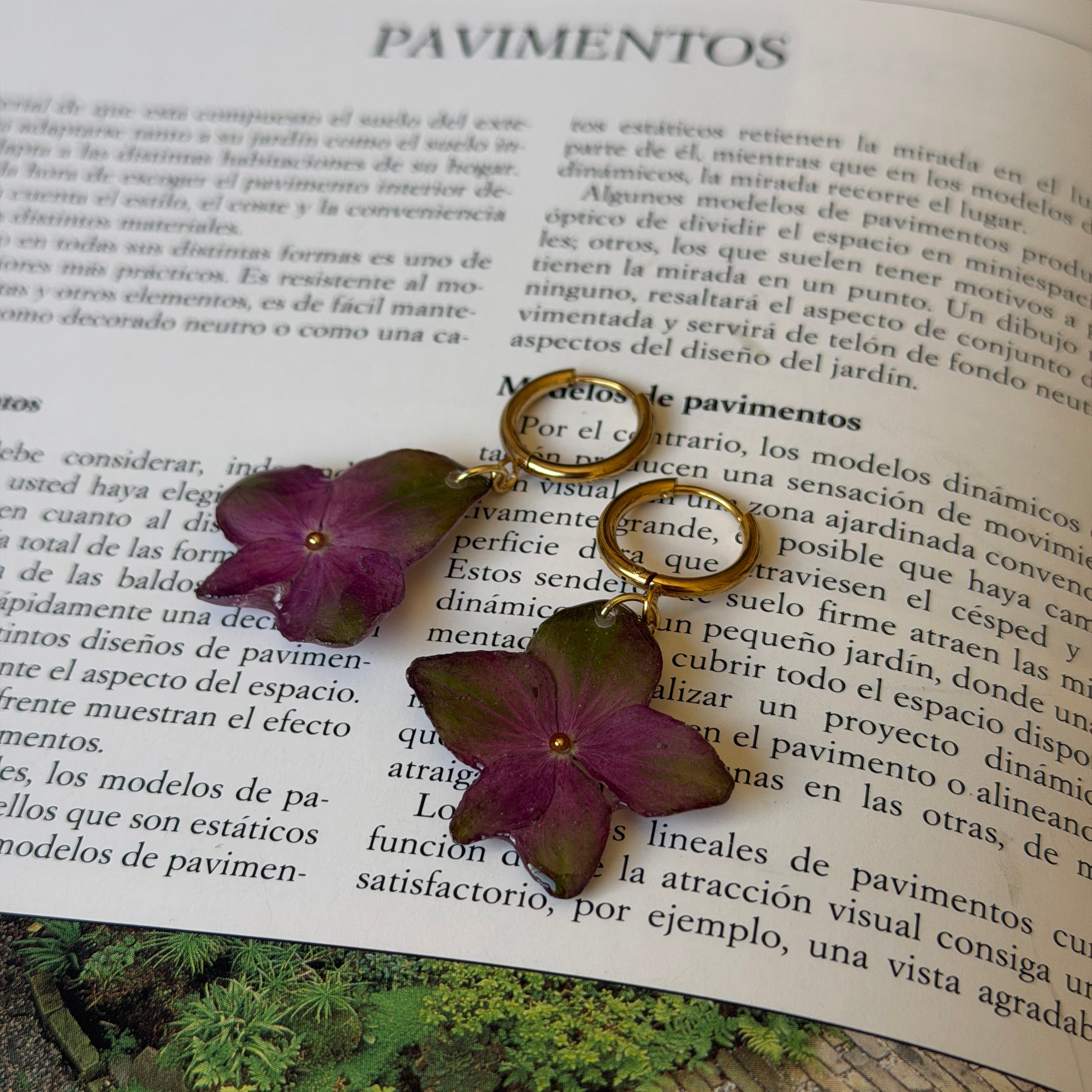 Pendientes de hortensia del fucsia al verde encapsulada en resina sobre las páginas de un libro