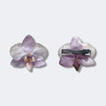 Pinza con orquídea lavanda encapsulada en resina sobre cocodrilo plateado, vista frontal y trasera