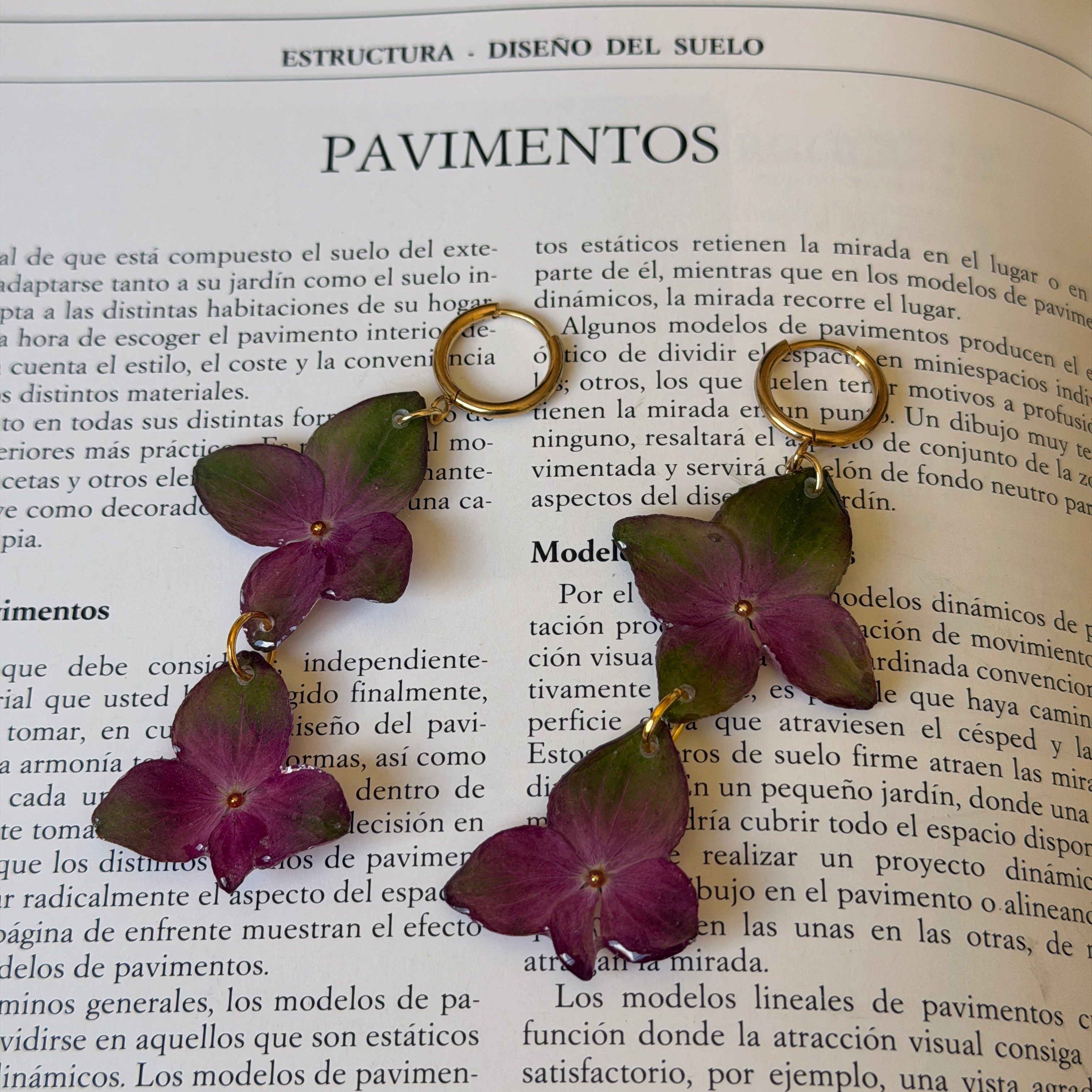 Pendientes de hortensia verde y fucsia encapsulada en resina sobre las páginas de un libro