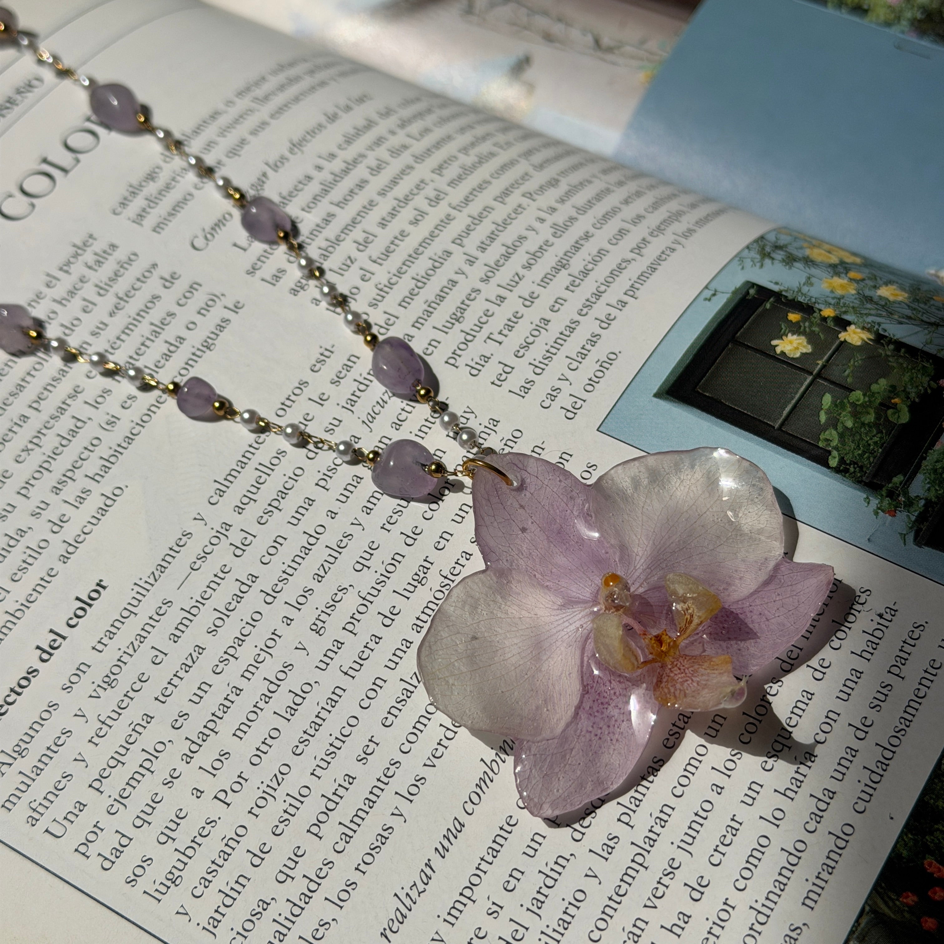 Colgante de orquídea lila real preservada en resina sobre una revista abierta