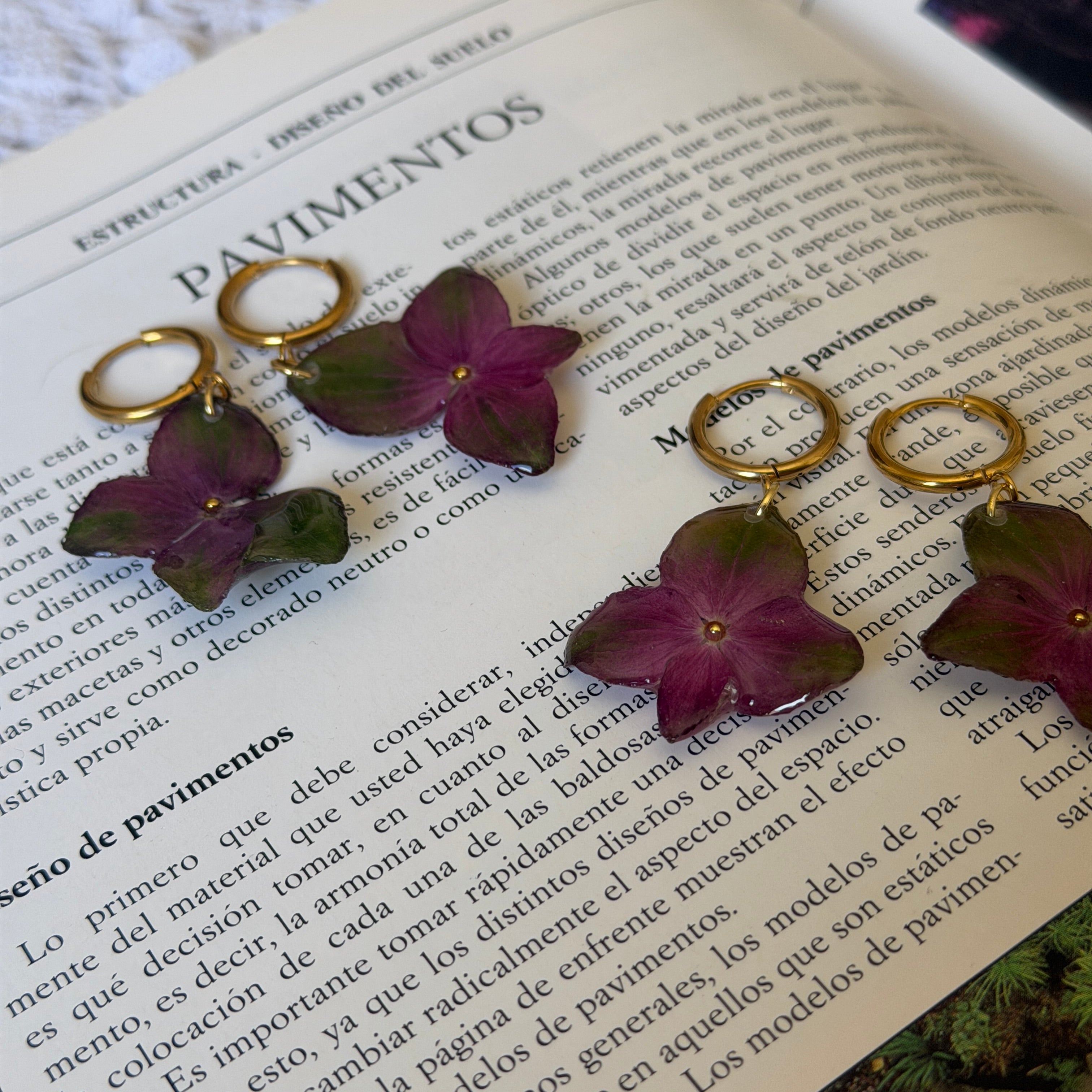 Par de pendientes de hortensia del fucsia al verde en resina sobre un libro abierto