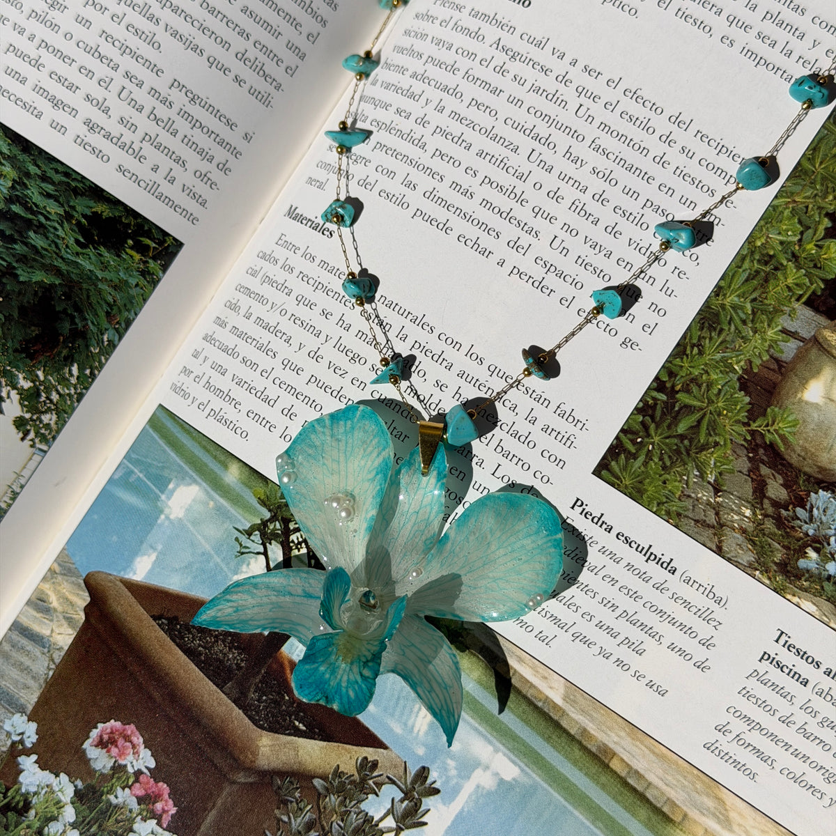 Collar de orquídea Dendrobium turquesa con cadena de turquesas sobre las páginas de un libro abierto