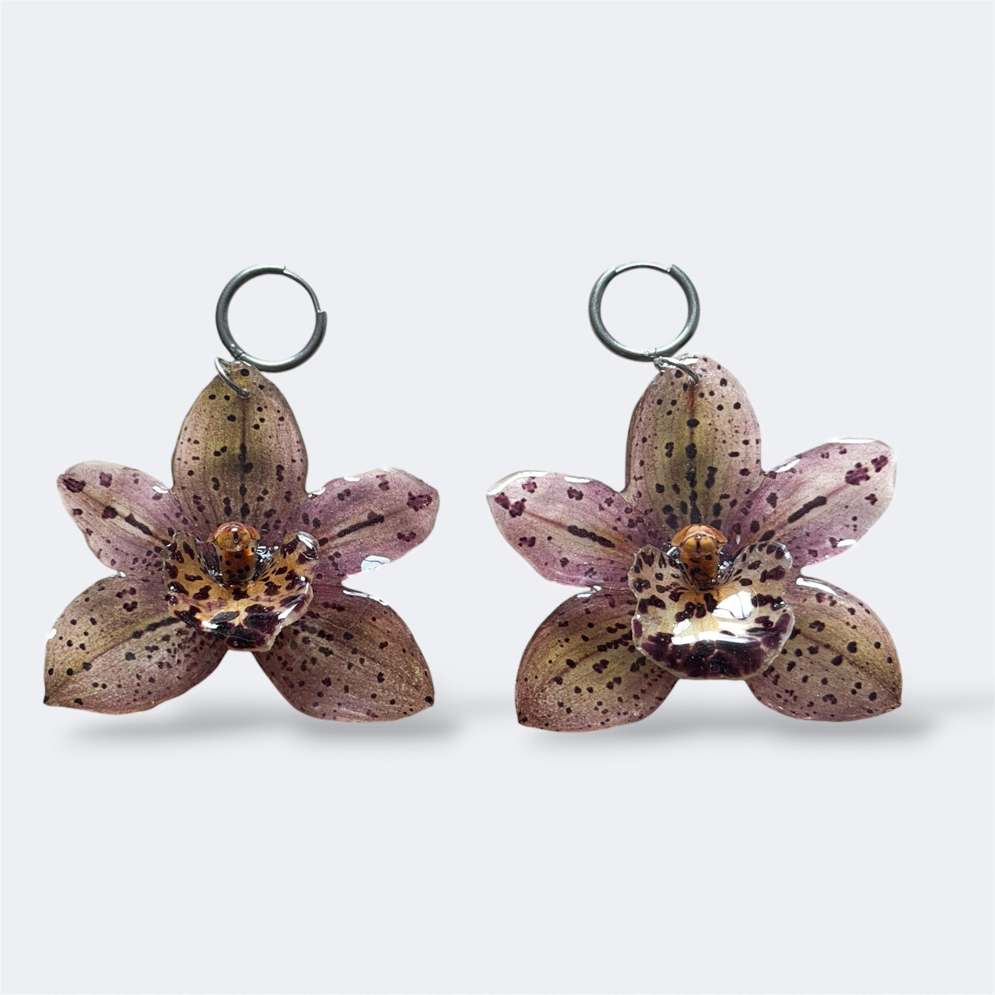 Pendientes con dos orquídeas malva moteadas encapsuladas en resina, sobre aros de acero inoxidable
