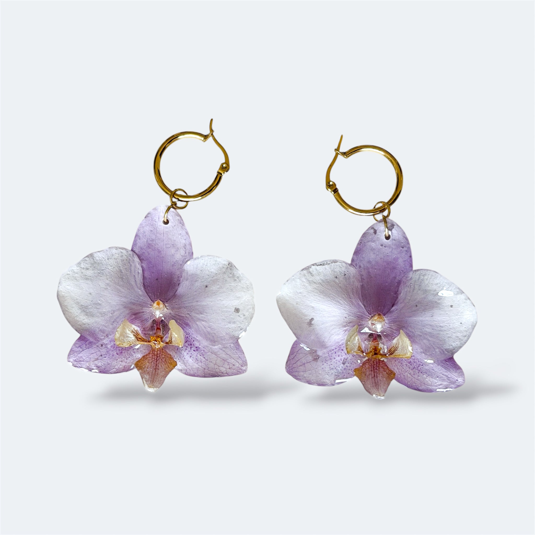 Pendientes con orquídea lila encapsulada en resina, sobre aros de acero inoxidable