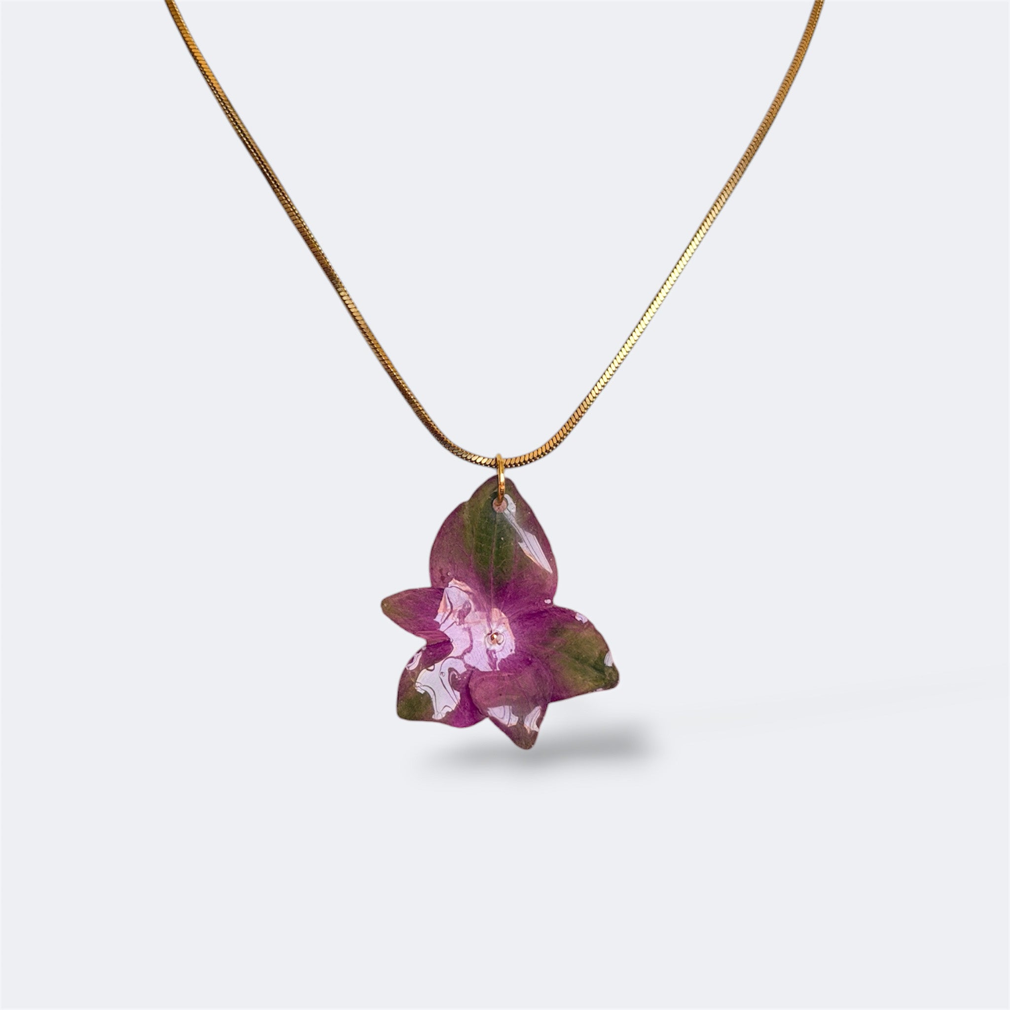Mujer llevando collar de hortensia morada y verde encapsulada en resina sobre el escote