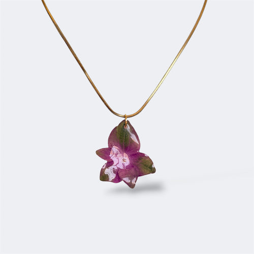 Mujer llevando collar de hortensia morada y verde encapsulada en resina sobre el escote