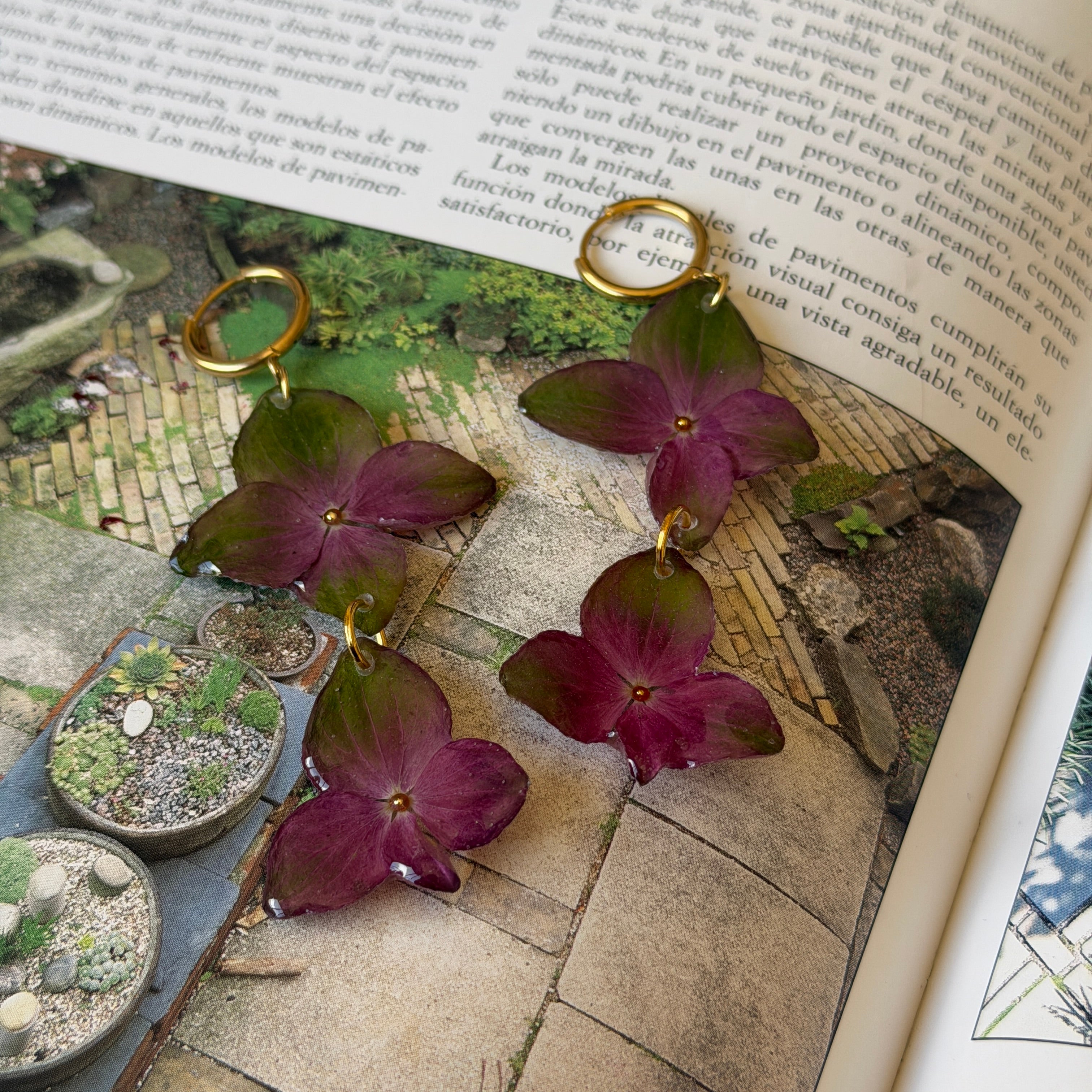 Pendientes de hortensia verde y fucsia en cascada sobre un libro abierto